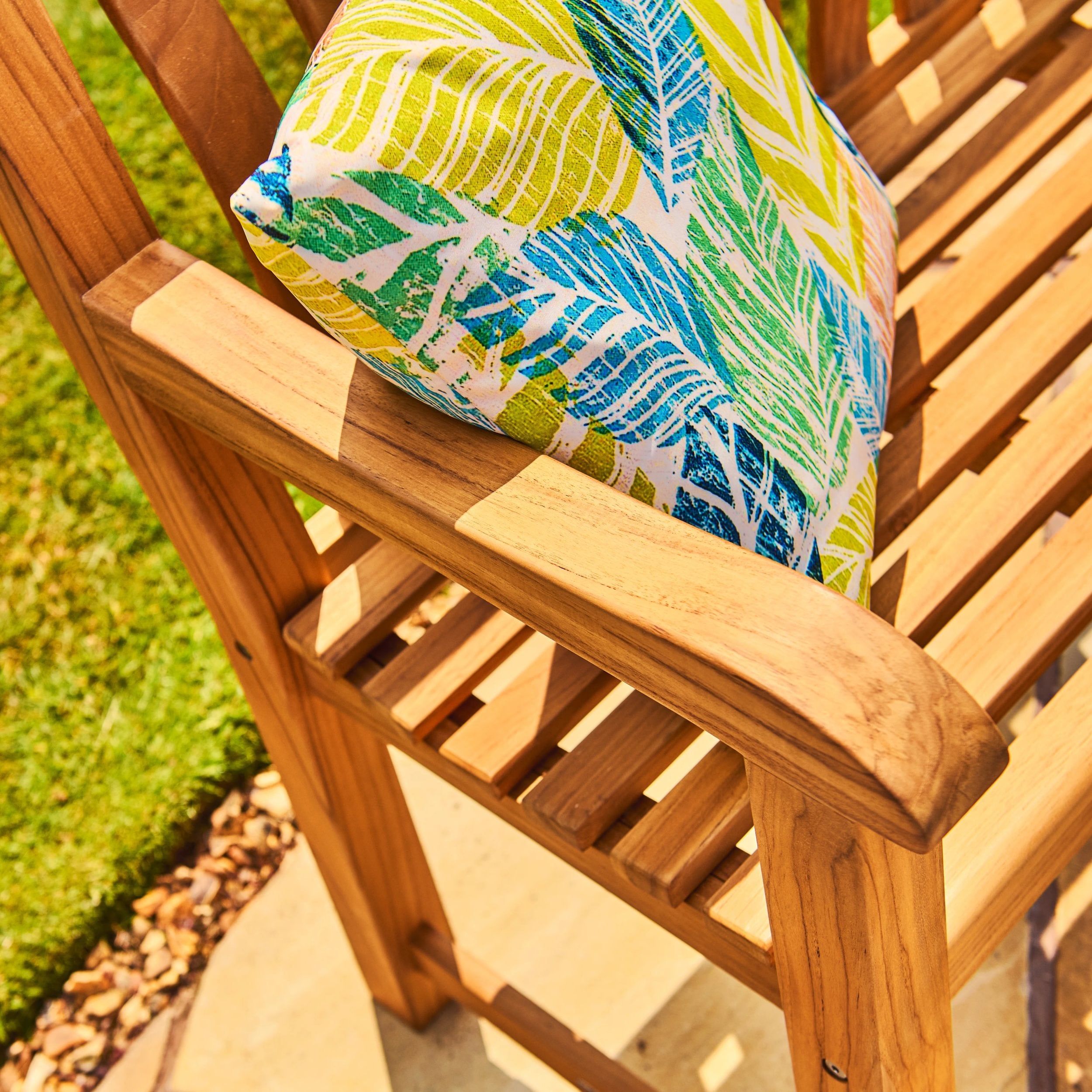 Wooden chair with a colorful leaf-patterned cushion on a grassy background