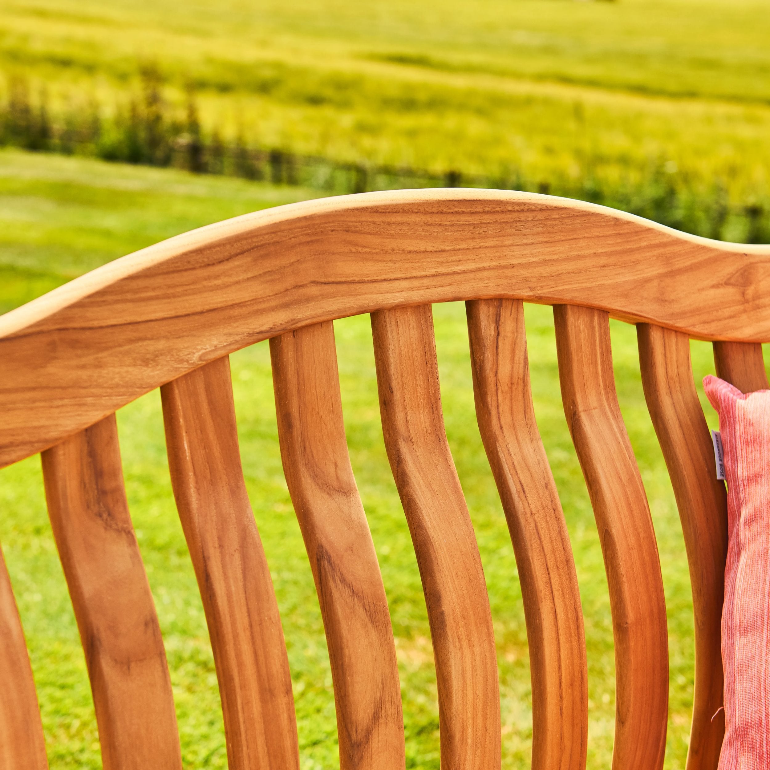 Close-up of a wooden bench seat with a blurred green field background