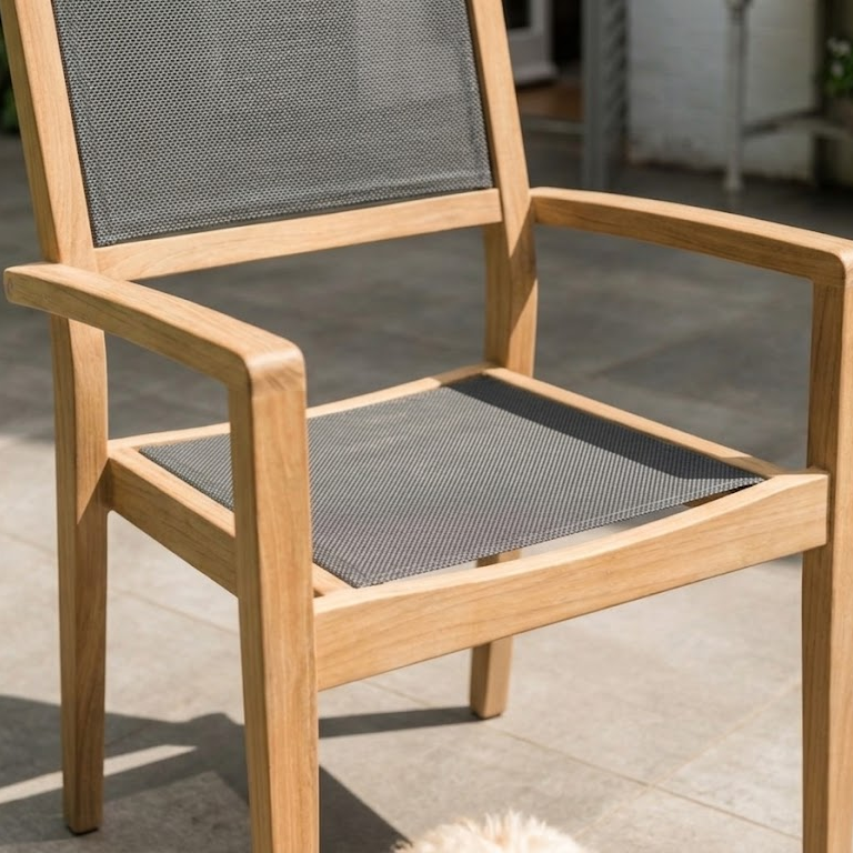 Wooden chair with dark mesh seat and back on a stone patio