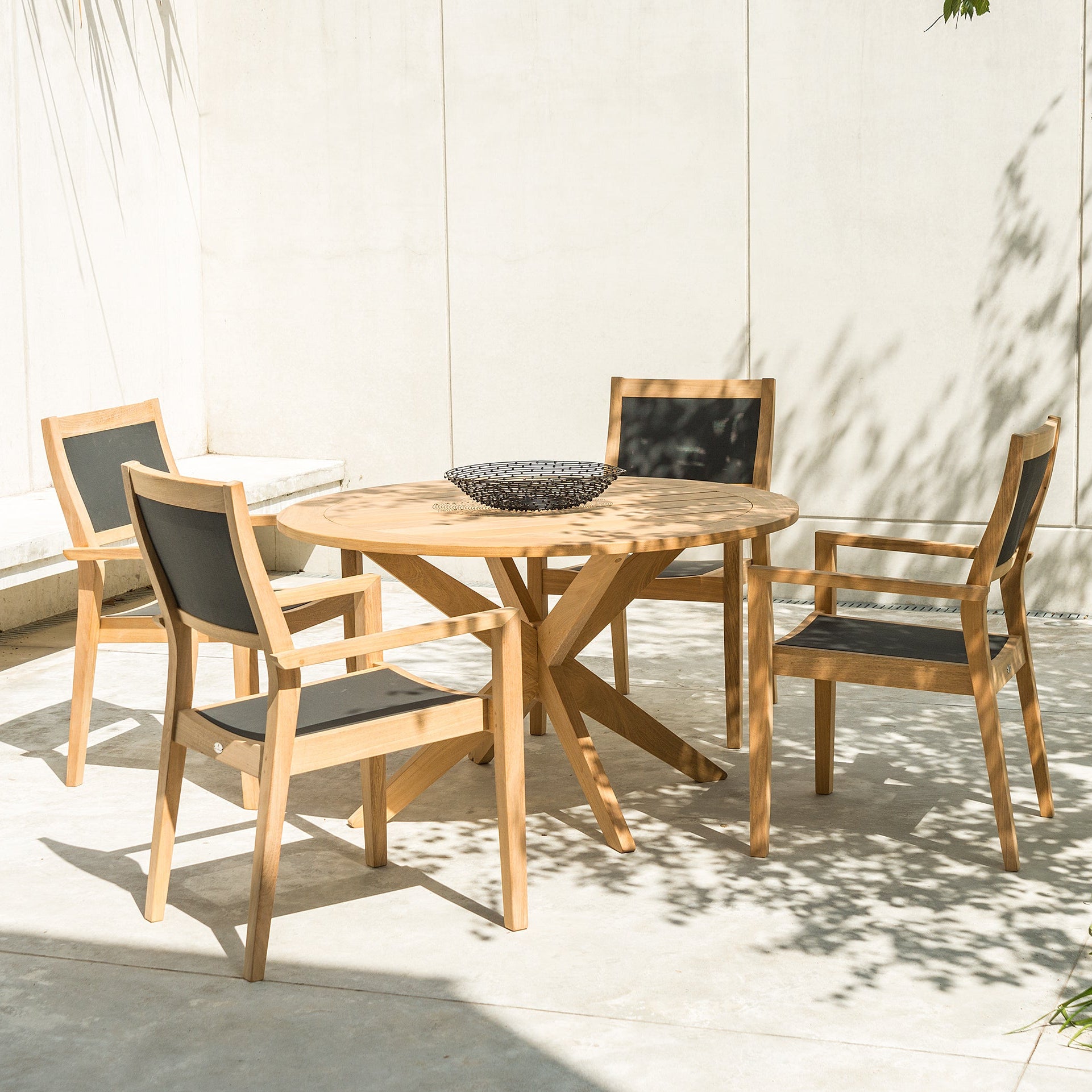 circular wooden table with 4 dining armchairs with black backs and seats