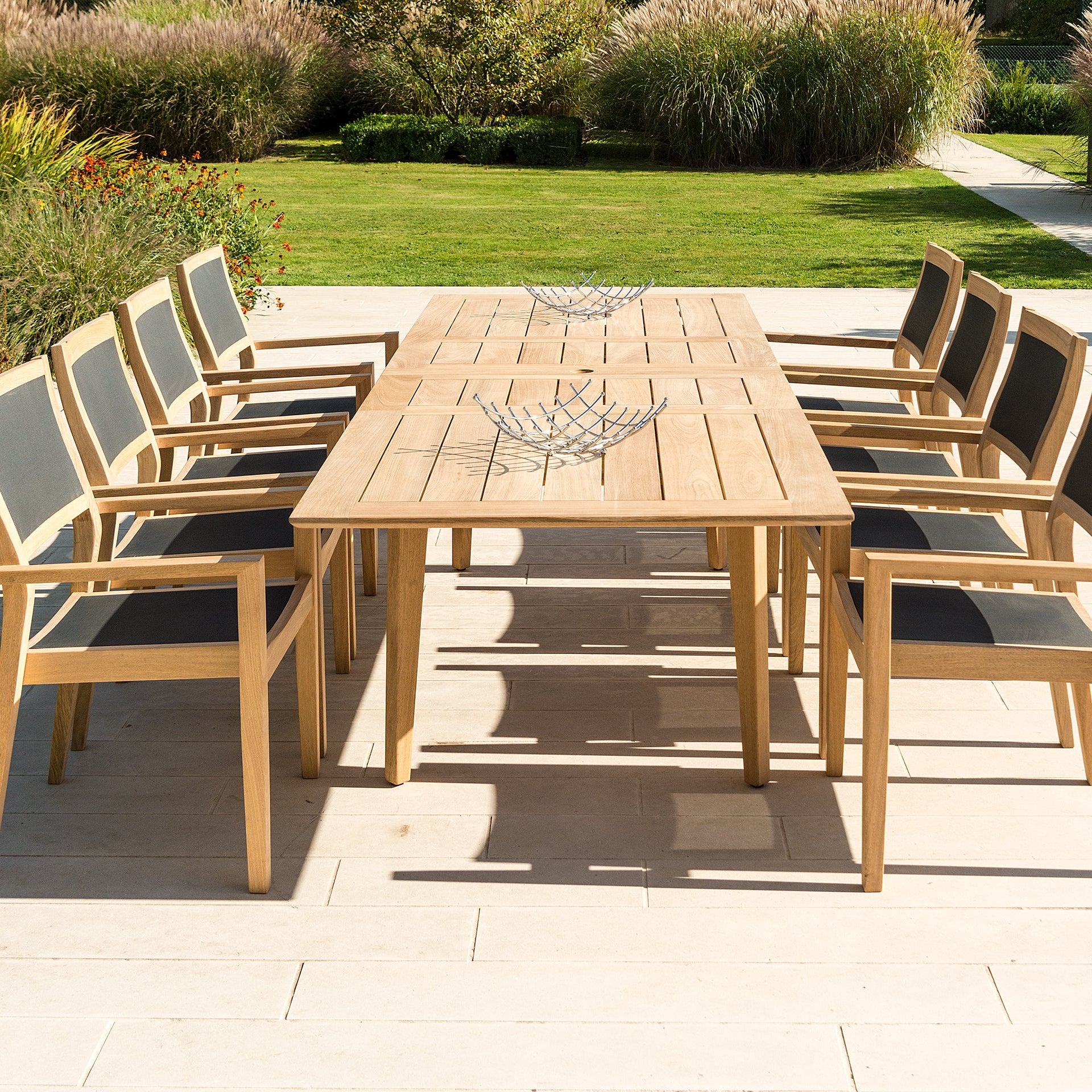 Extended roble dining table with 8 chairs positioned equally on either side on a patio area