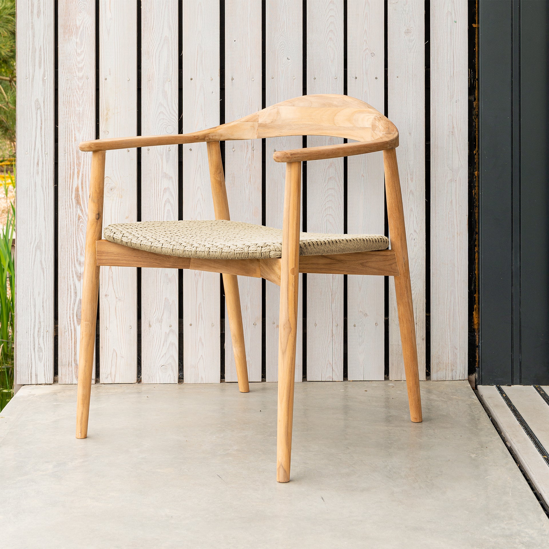 Curved outdoor armchair beautifully styled with woven seat pad