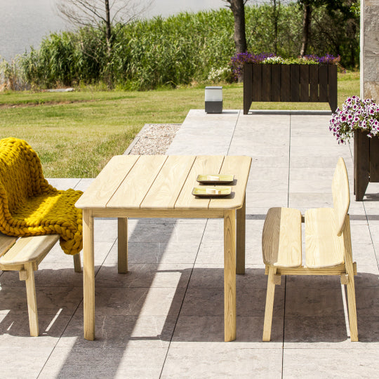 Outdoor pine patio set with wooden table and stylish bench chairs on a tiled patio.