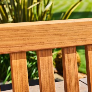 Close-up of wooden bench slats with green foliage in the background