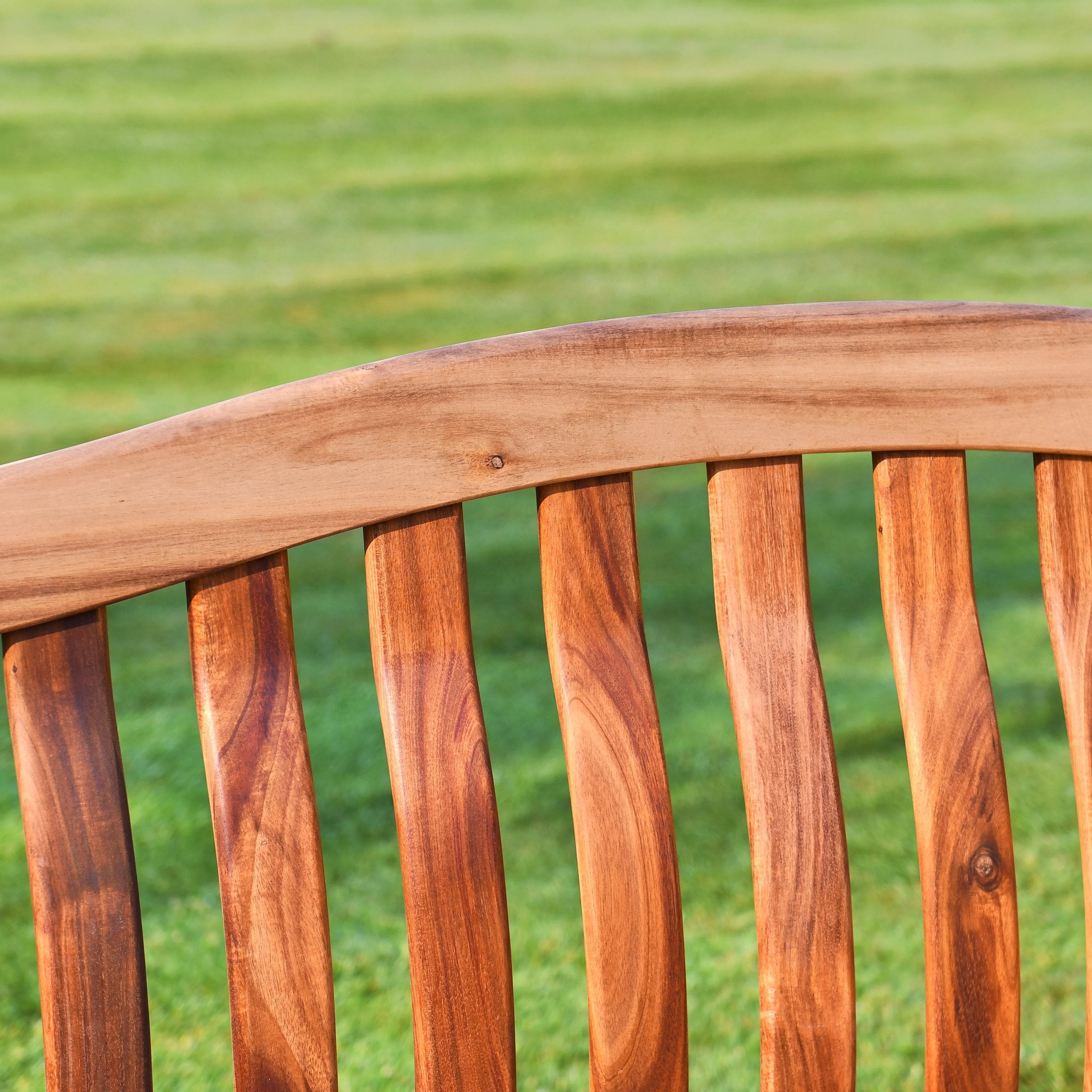 Wooden bench seat with a blurred green grass background