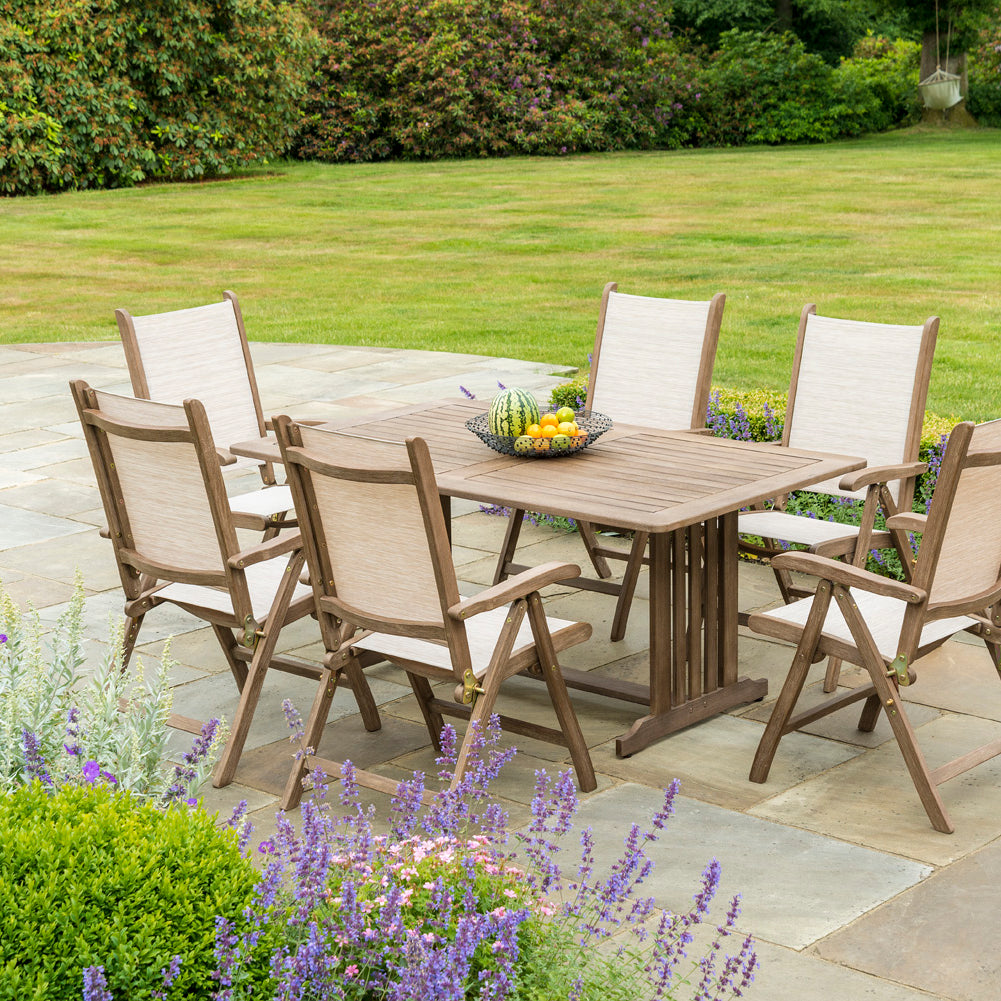 6 folding outdoor chairs and a rectangular table on a patio near a lawn
