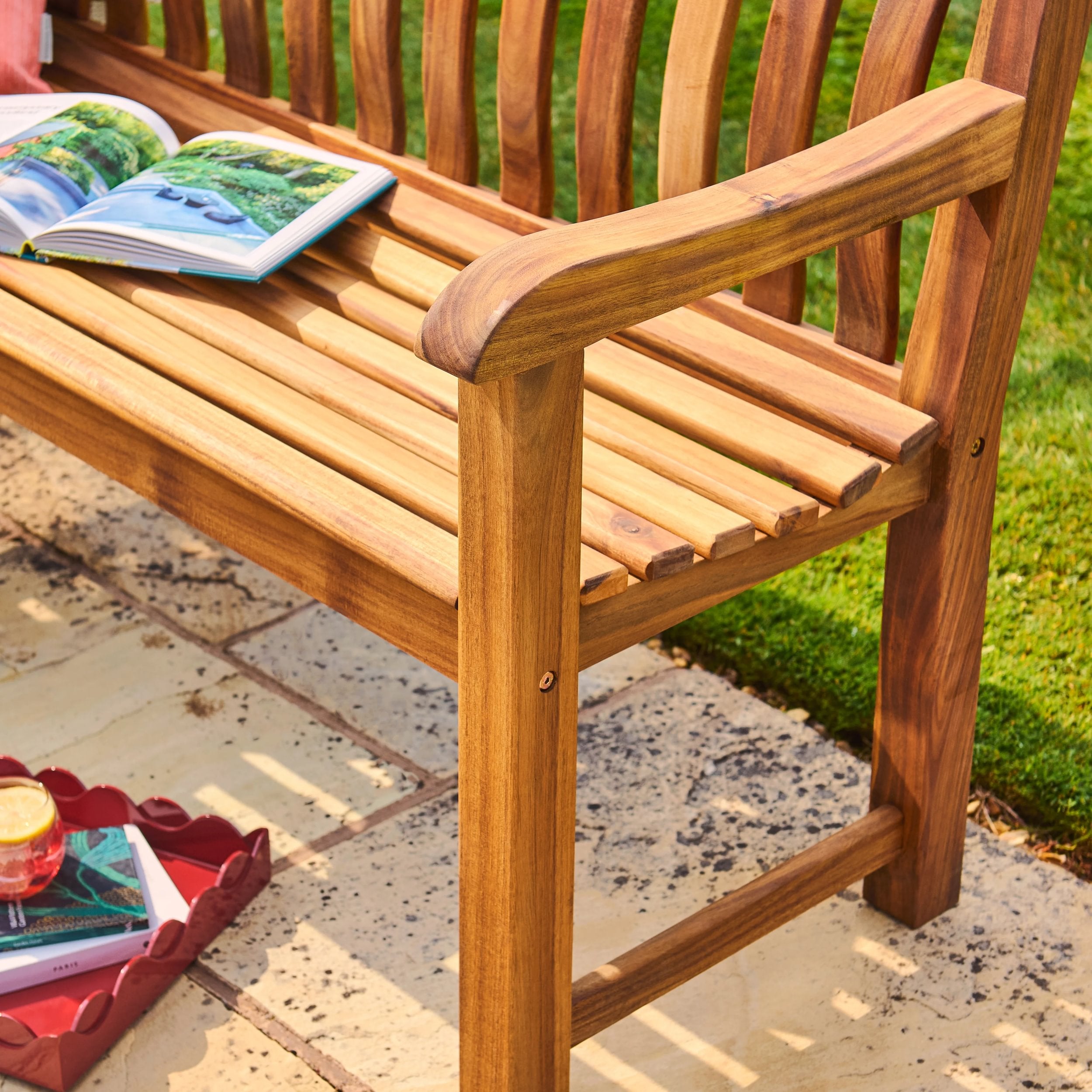 Wooden bench with a book and red tray on a stone patio
