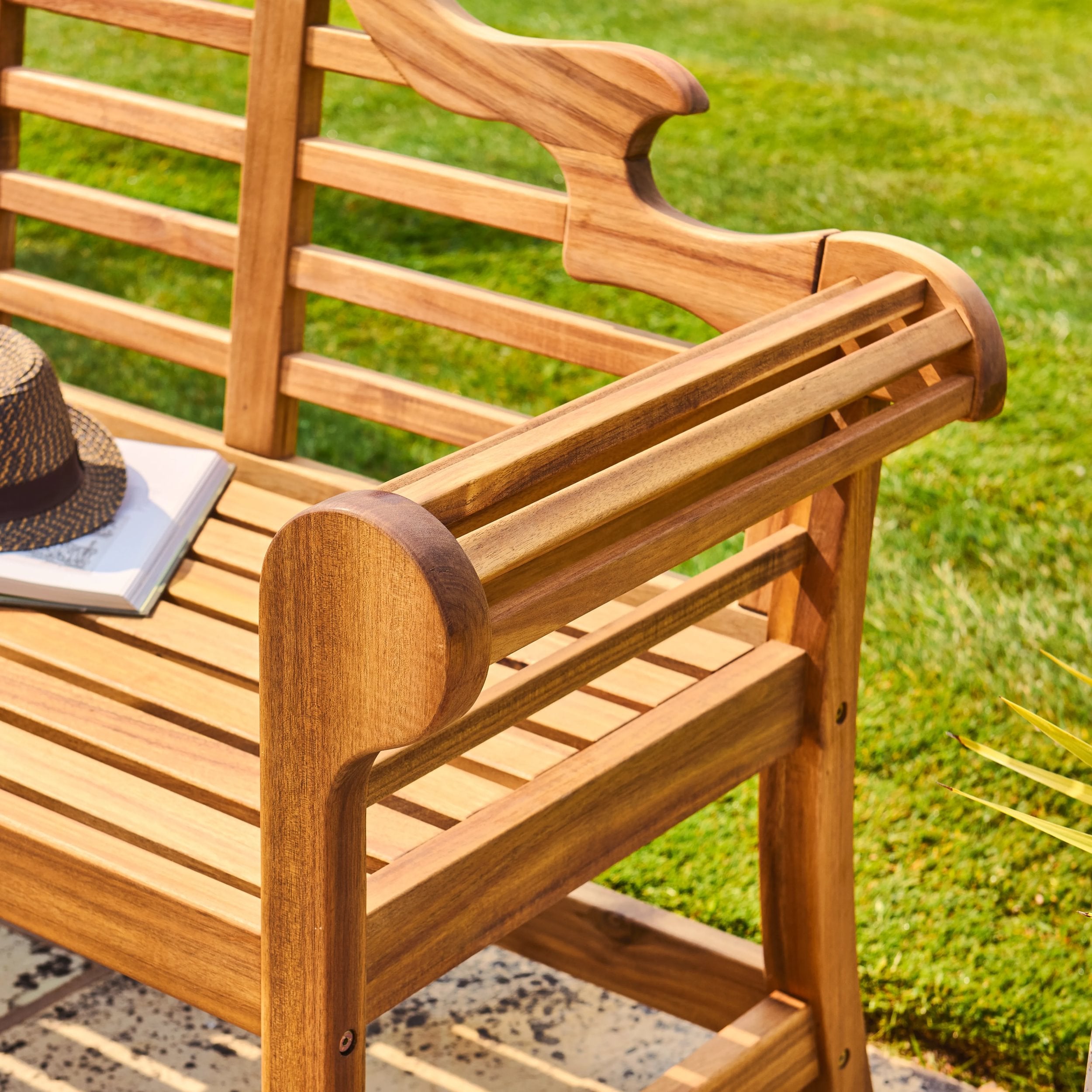 Wooden bench with a hat and book on a grassy background