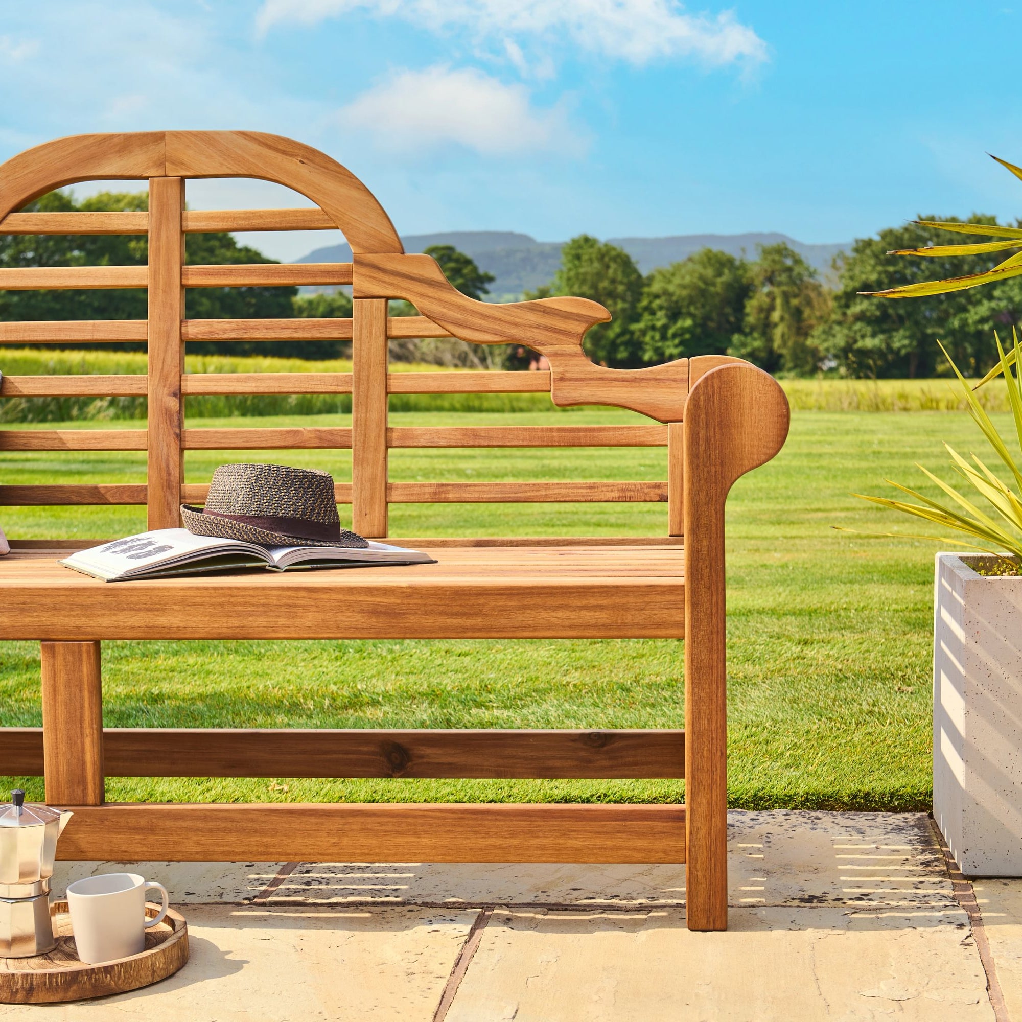 Wooden bench with a hat, book, and small tray in a garden setting