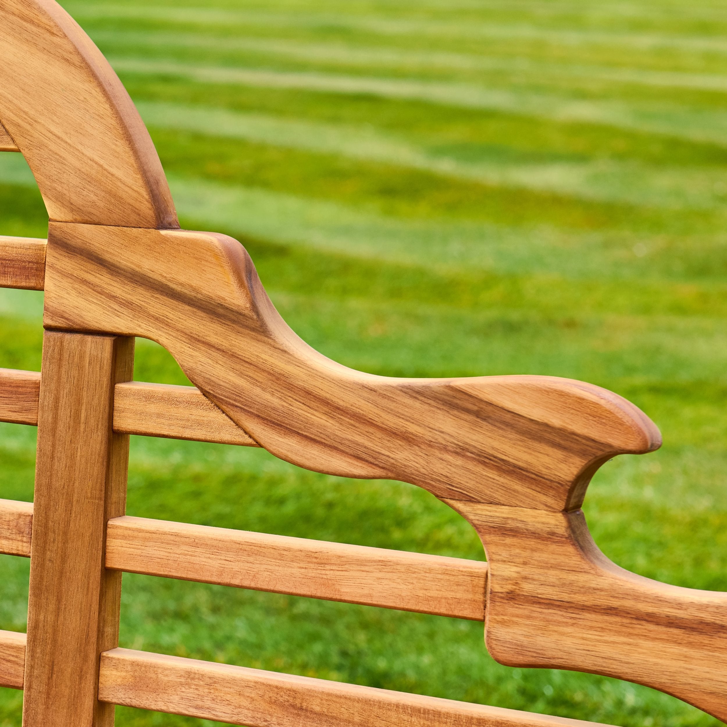 Wooden chair backrest with a blurred green grass background