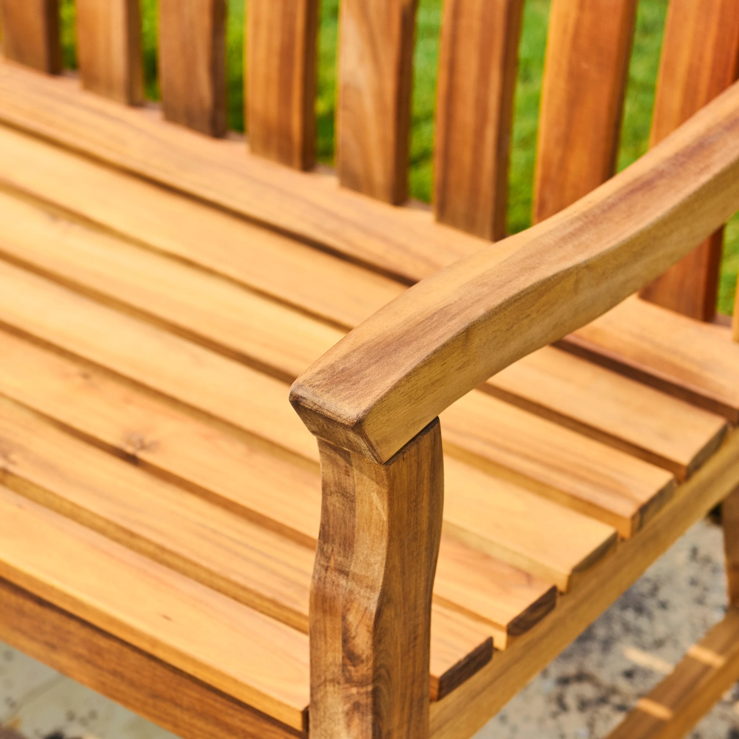 Close-up of a wooden bench with a blurred green background