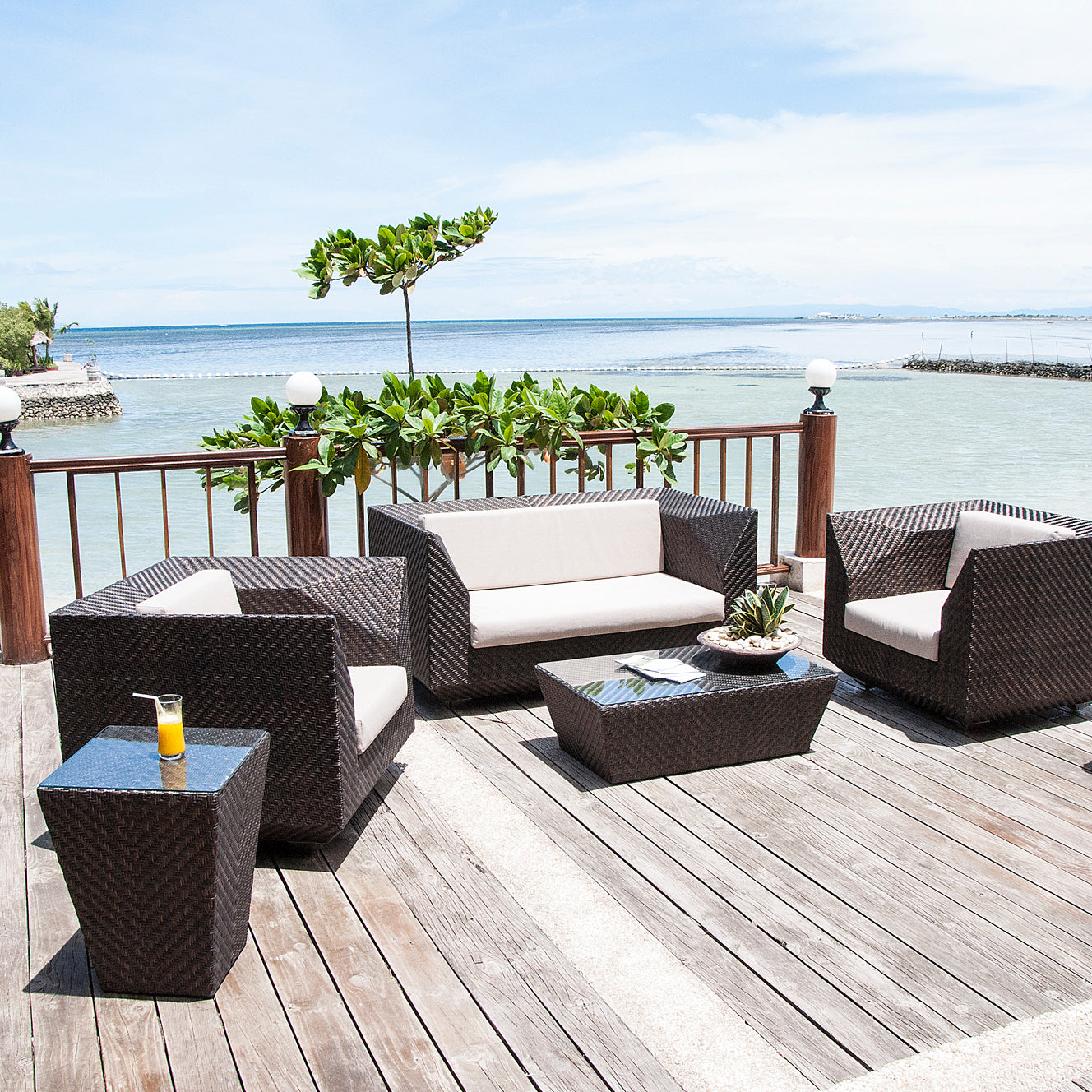Outdoor furniture set on a wooden deck with a scenic view of water and sky.