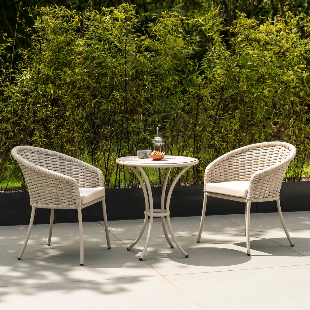 Beige rope-woven outdoor chair set with a small table on a patio.