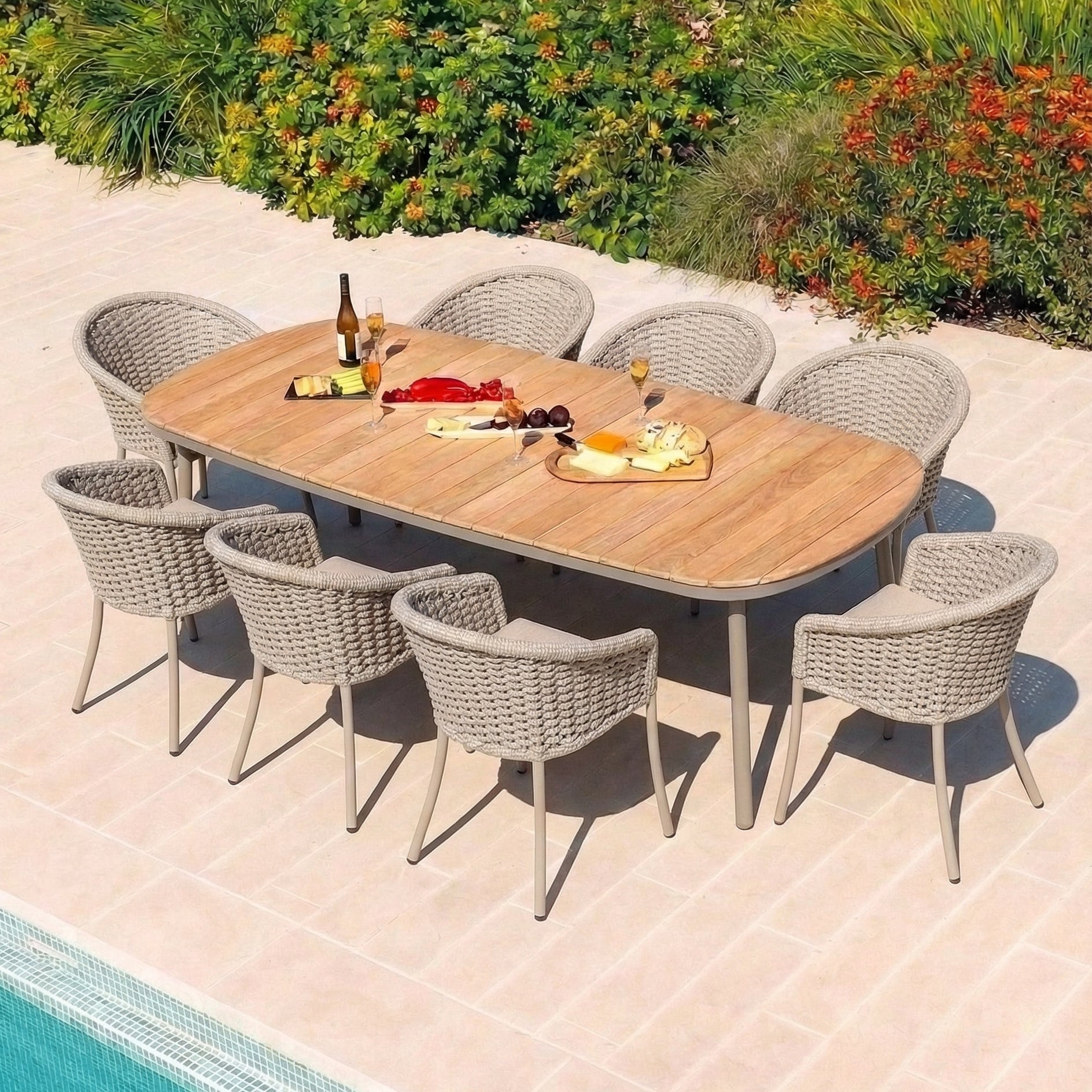 Outdoor dining setup with a wooden table and woven rope chairs by a pool