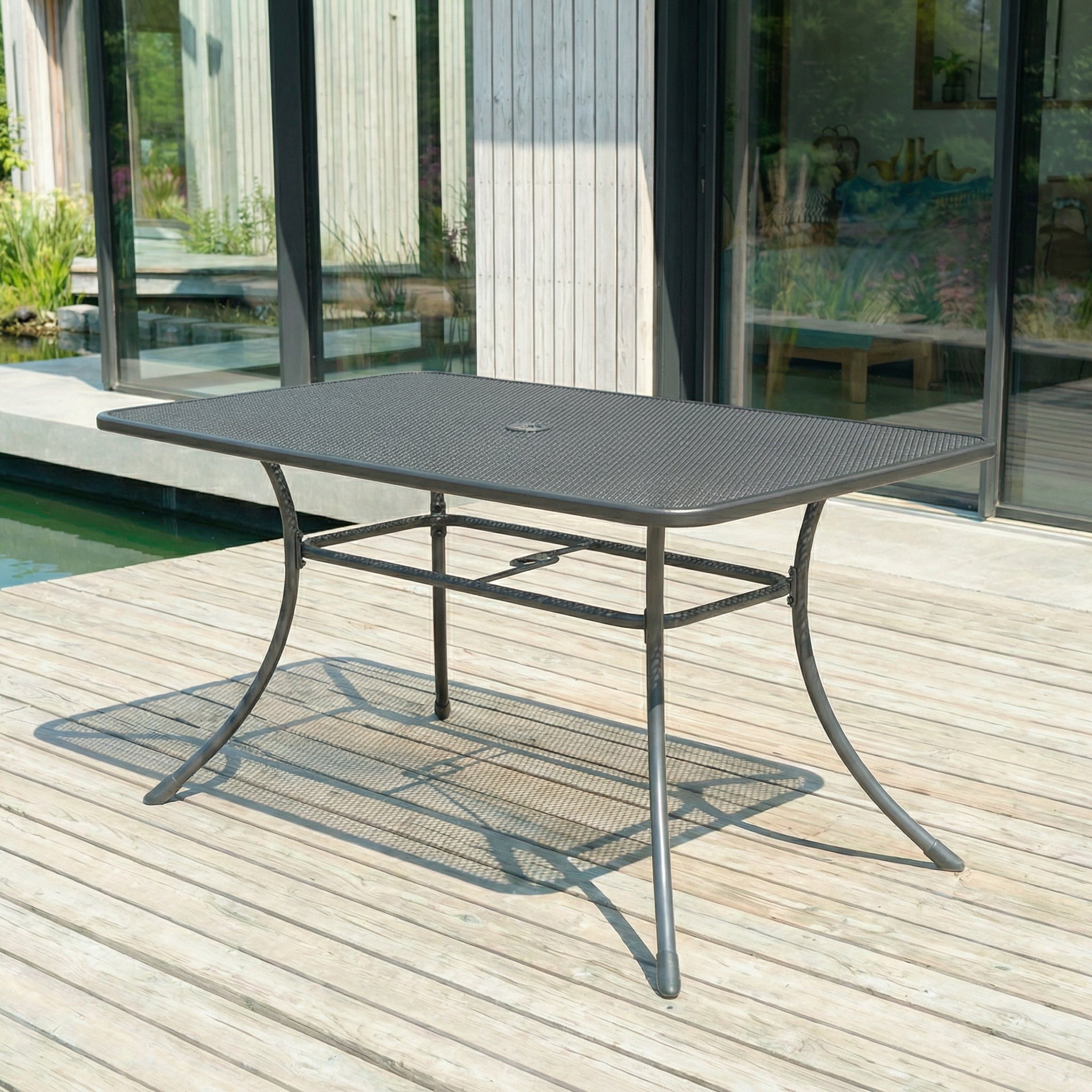 Outdoor metal table on a wooden deck with a modern house in the background