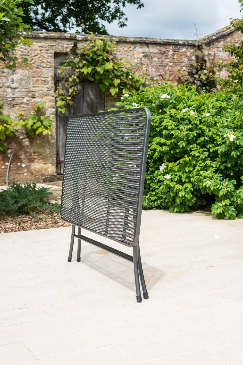 Portofino rectangular table in a folded position showing how compact this black mesh table can fold