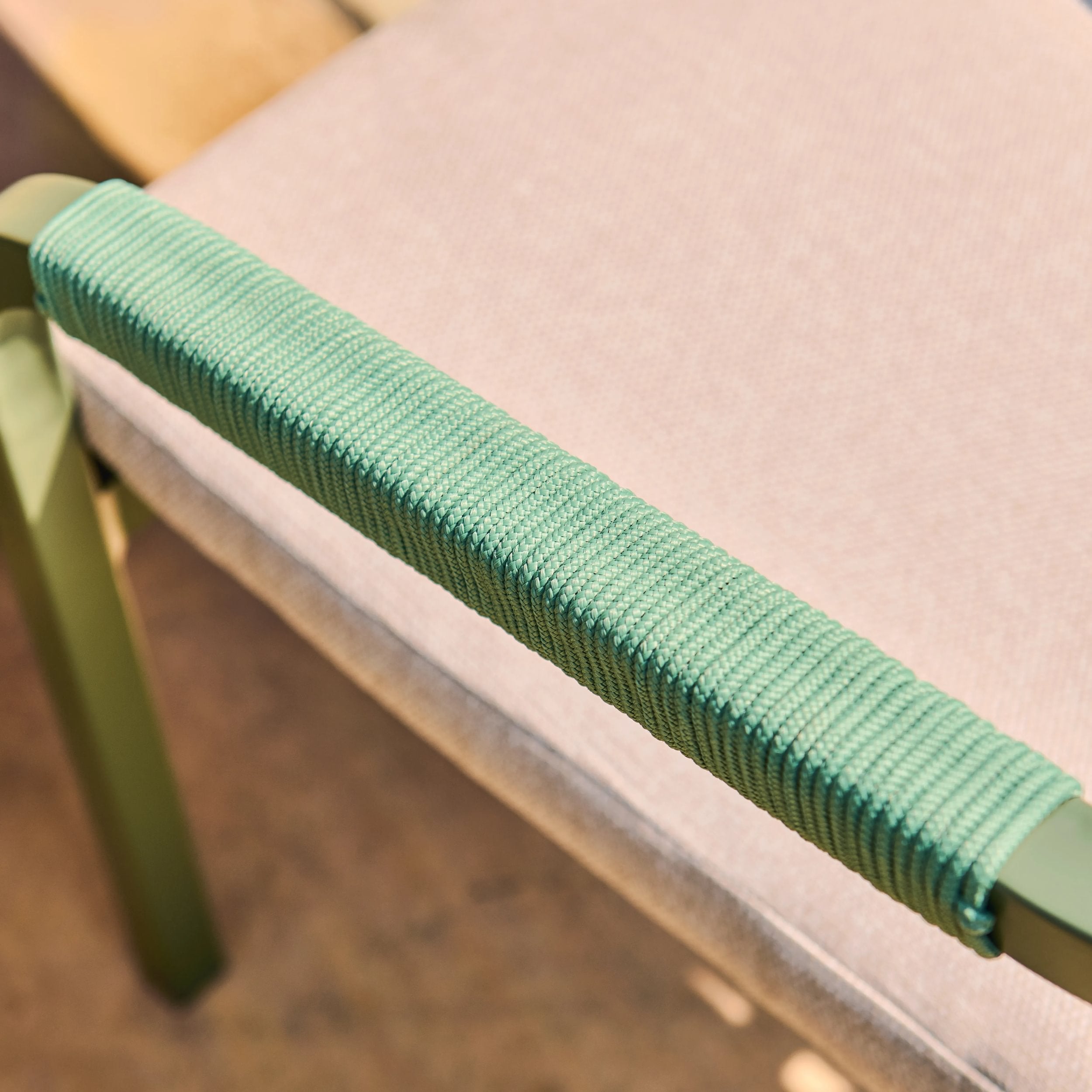 Close-up of a green woven handle on a chair with a blurred background