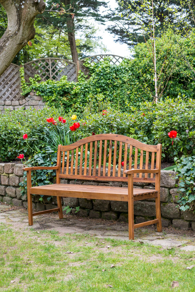 Wooden bench in a garden setting with flowers and stone wall