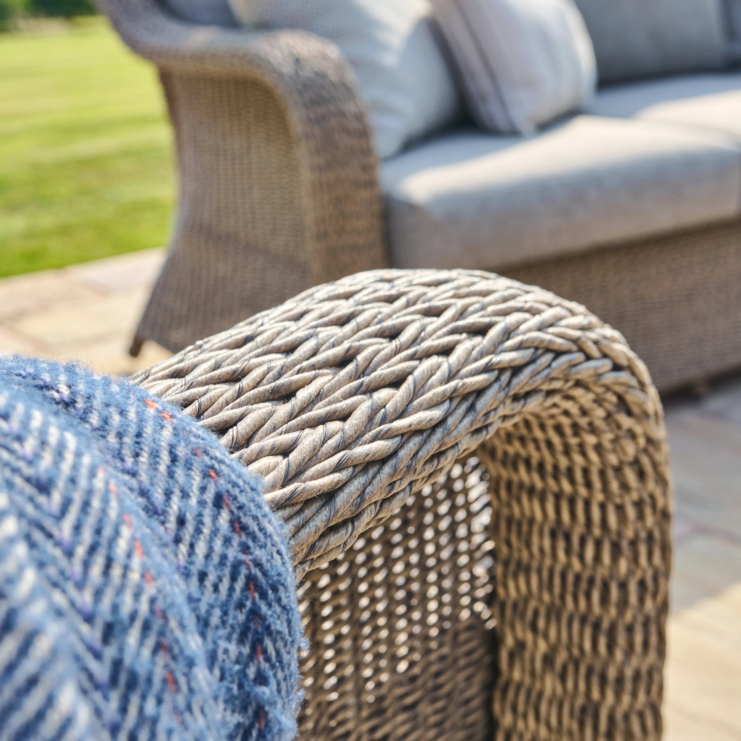 Close-up of a woven chair arm with a blurred outdoor setting