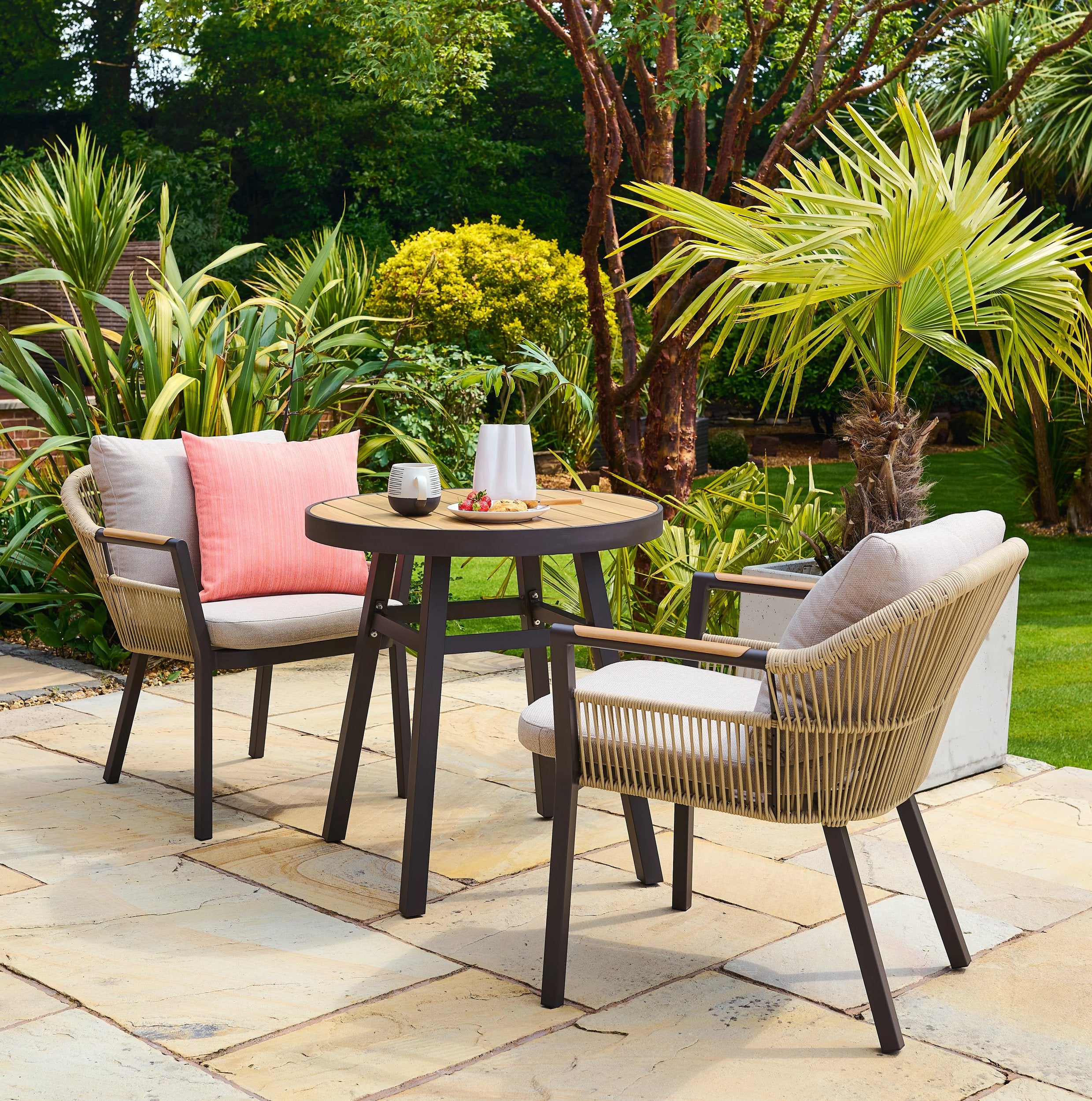 Outdoor patio bistro set with chairs and a table in a garden setting