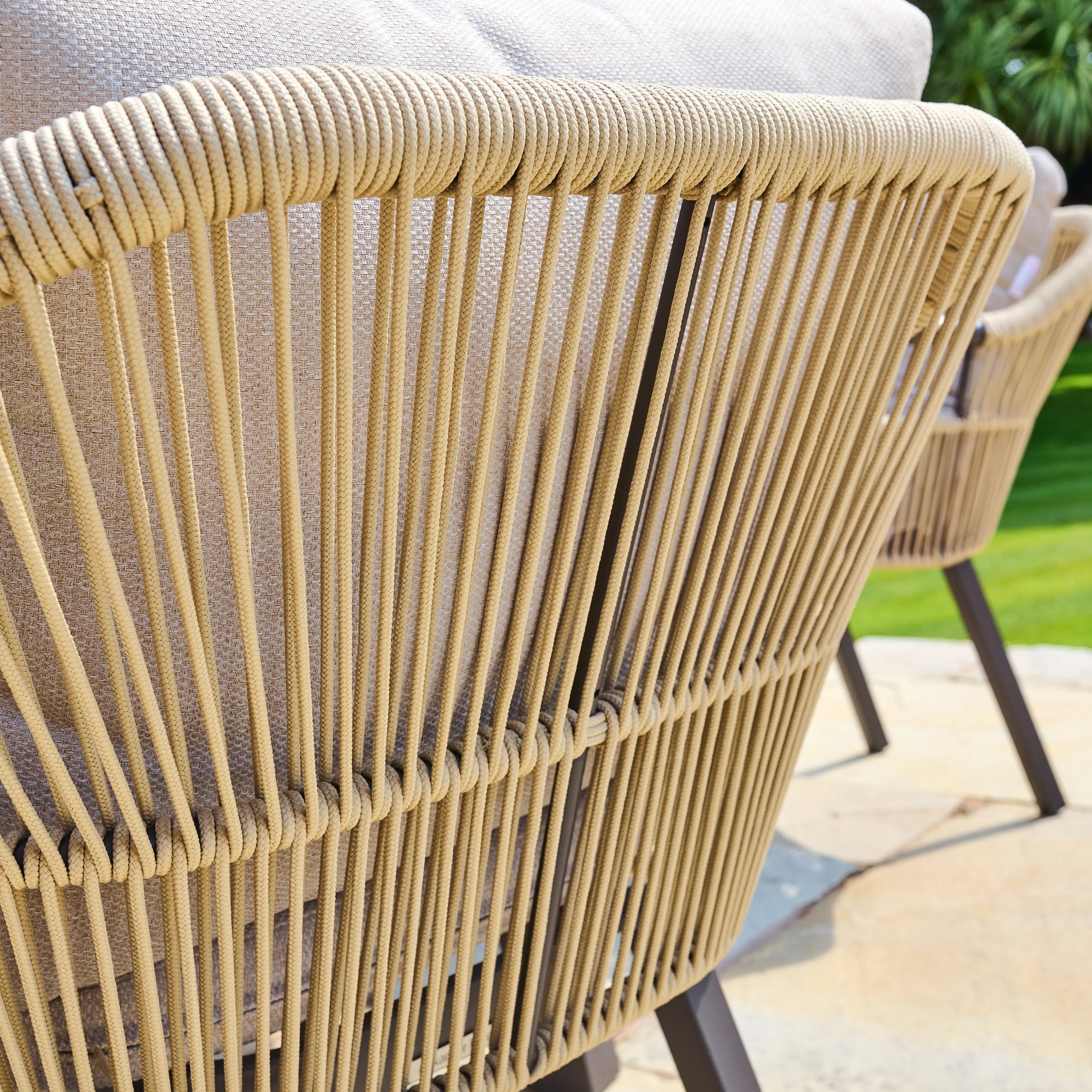 Close-up of a woven rope chair with a blurred outdoor background