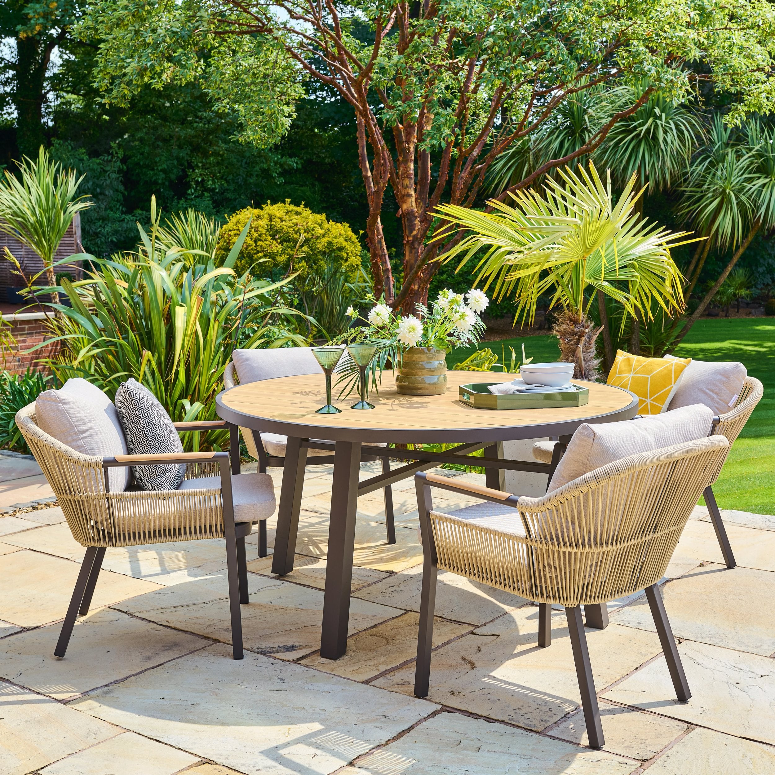 Outdoor patio dining set with round table and chairs in a garden setting