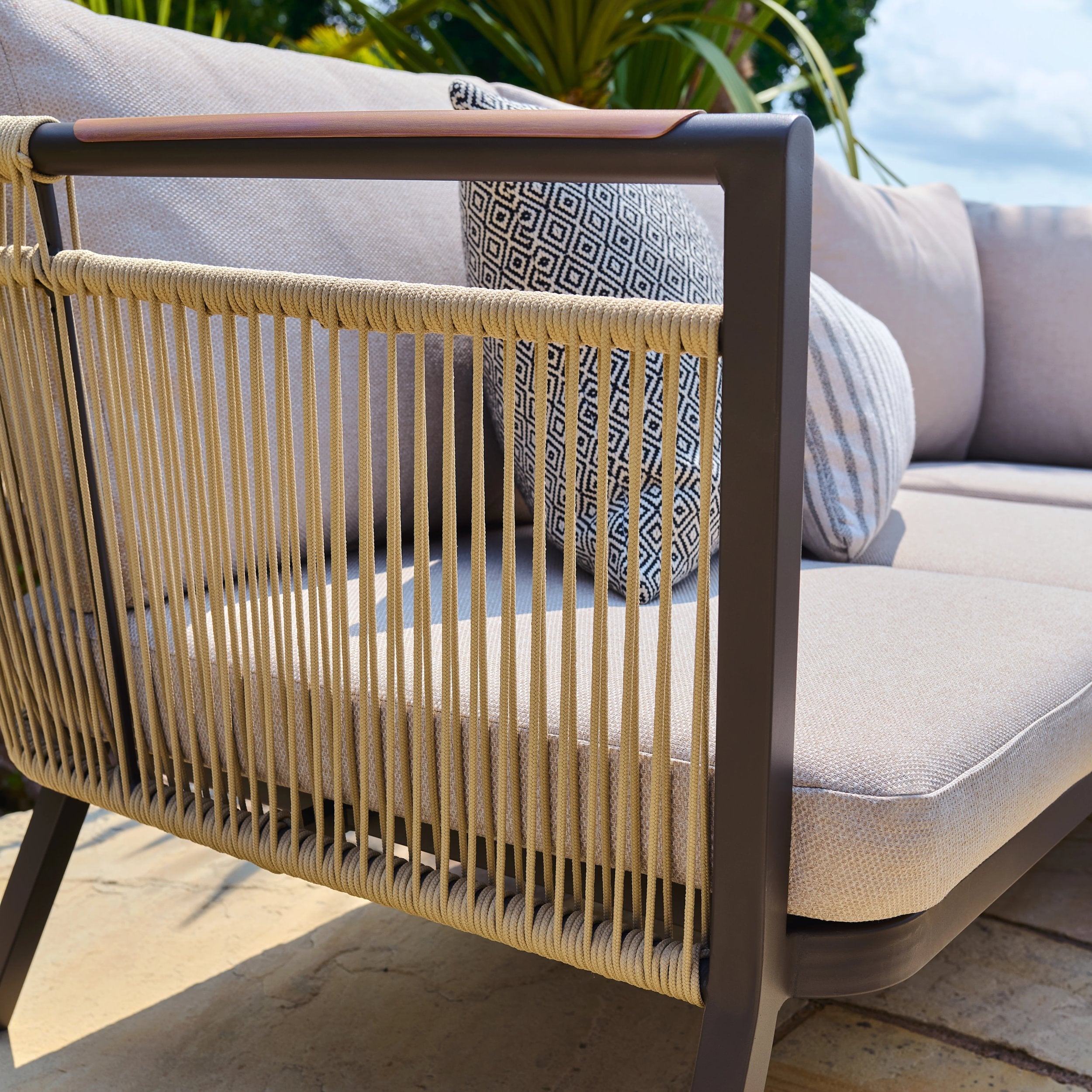 Outdoor furniture with woven armrest and cushioned seat on a patio