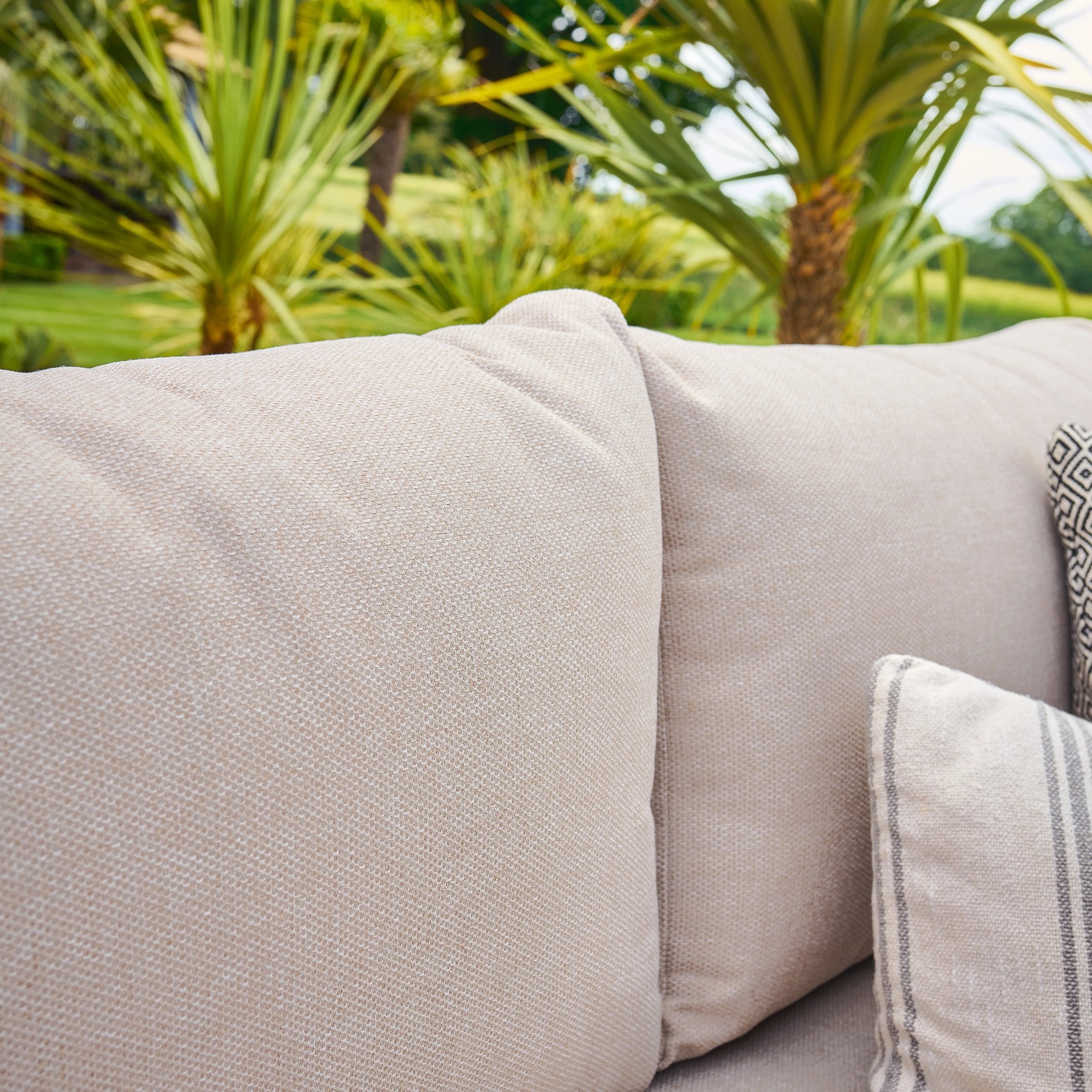 Beige outdoor sofa with a palm tree in the background