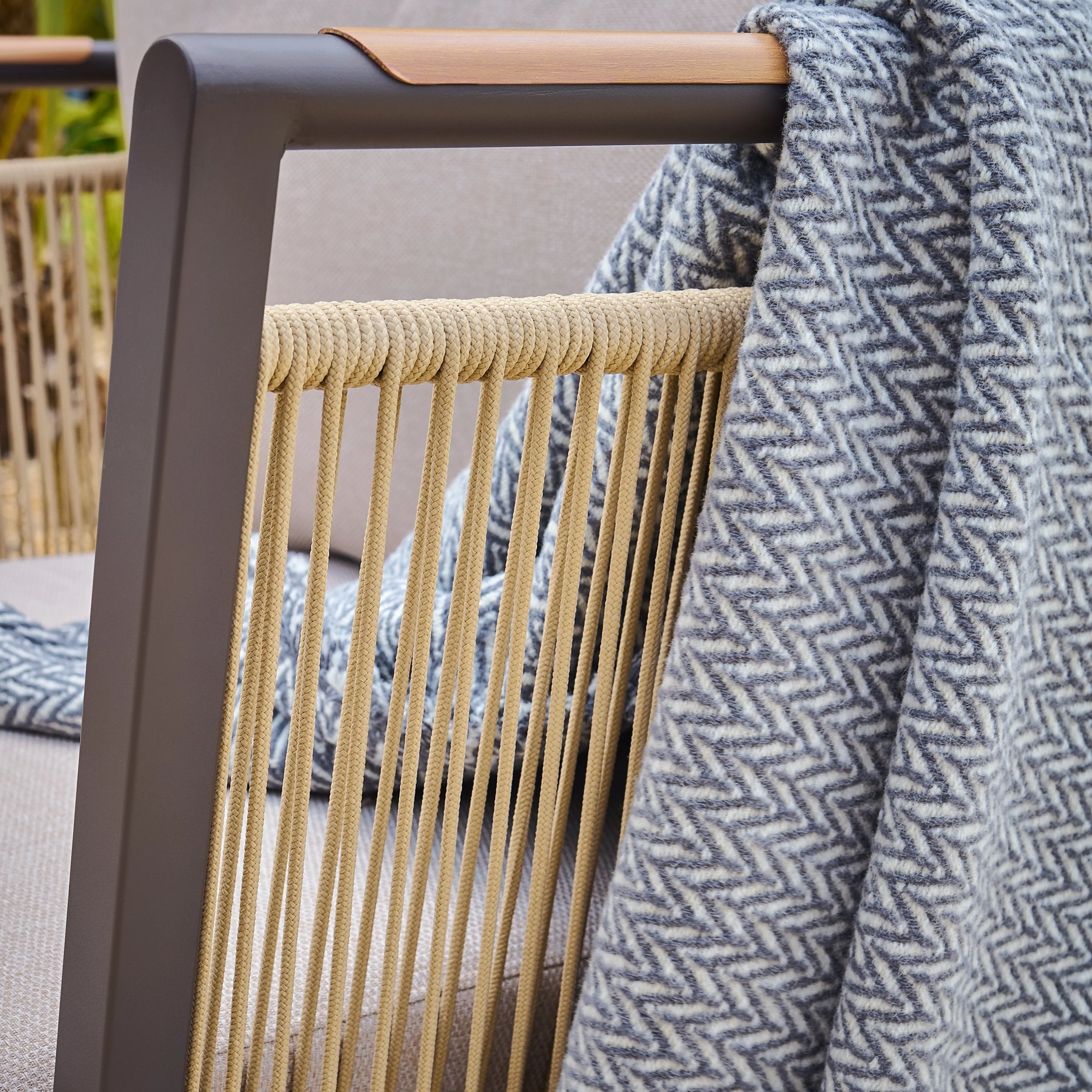 Chair arm with woven rope fabric on a blurred outdoor background