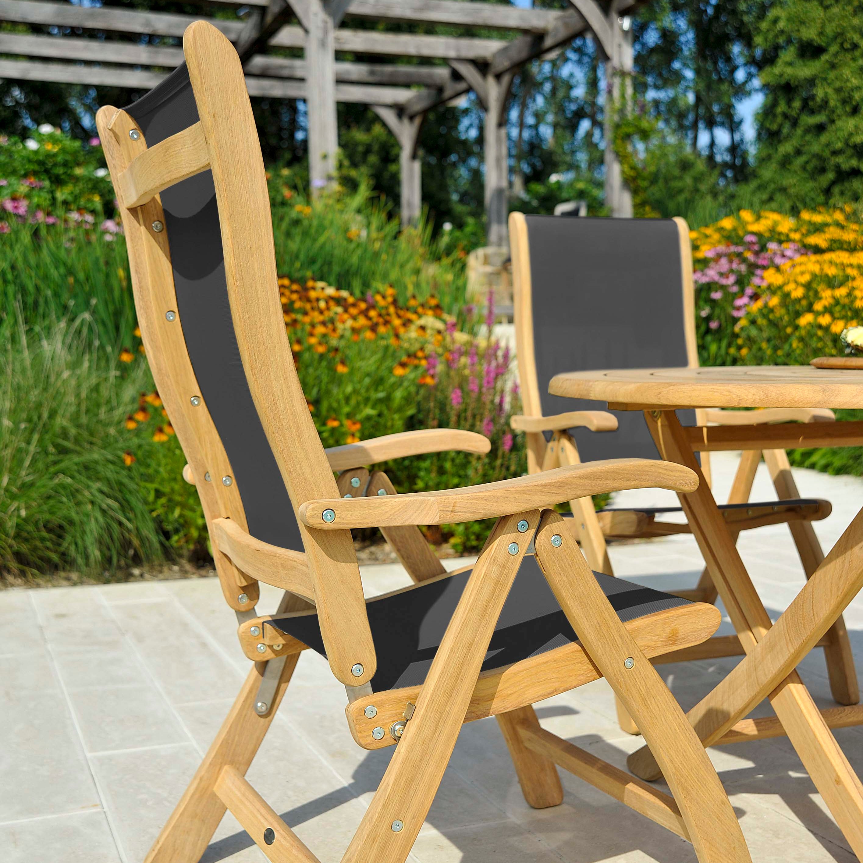 Two roble wood folding carver chairs on a patio