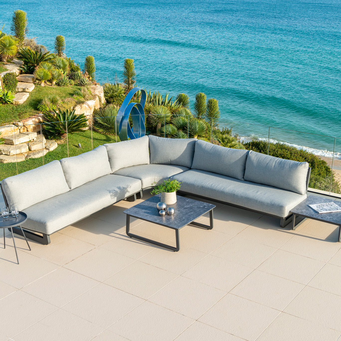 Rimini outdoor modular sofa in a corner shape with coffee tables and the sea in the background
