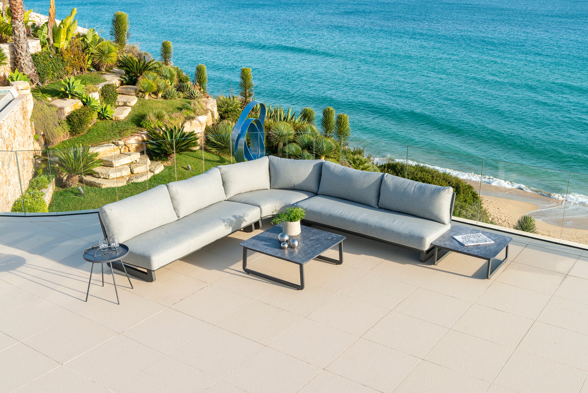 Rimini outdoor modular sofa in a corner shape with coffee tables and the sea in the background