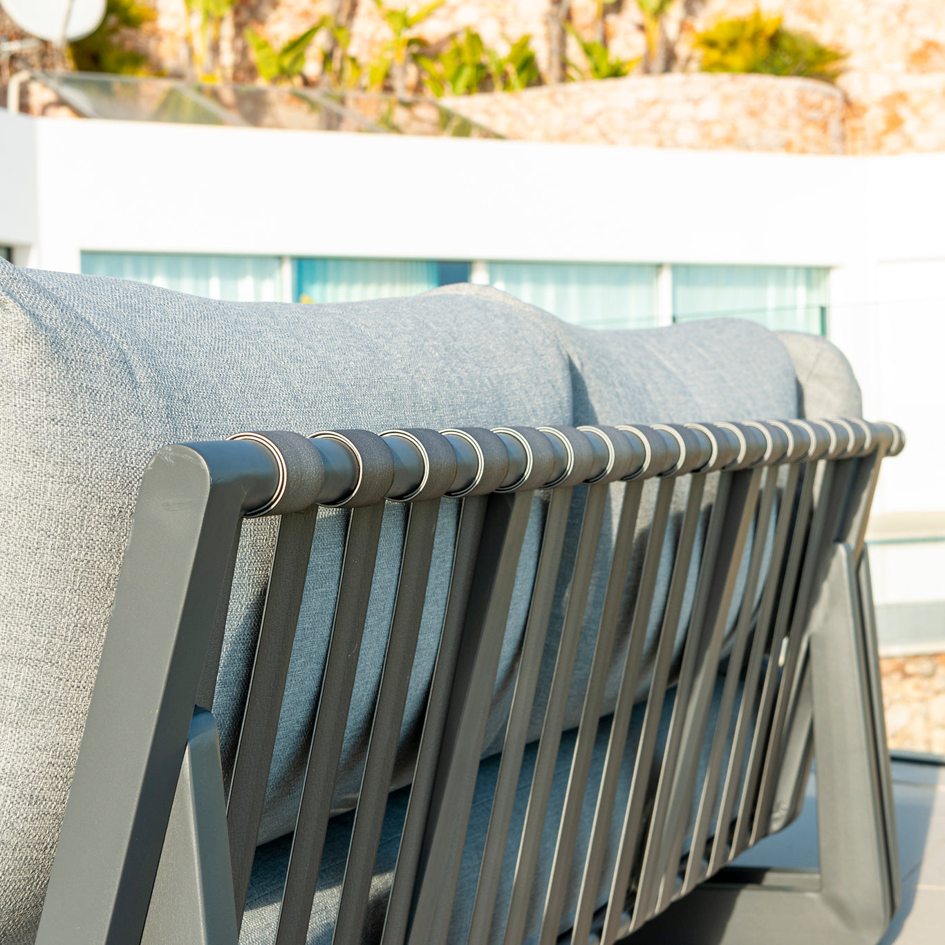 Grey outdoor modular sofa with metal frame on a patio close-up image of detail.