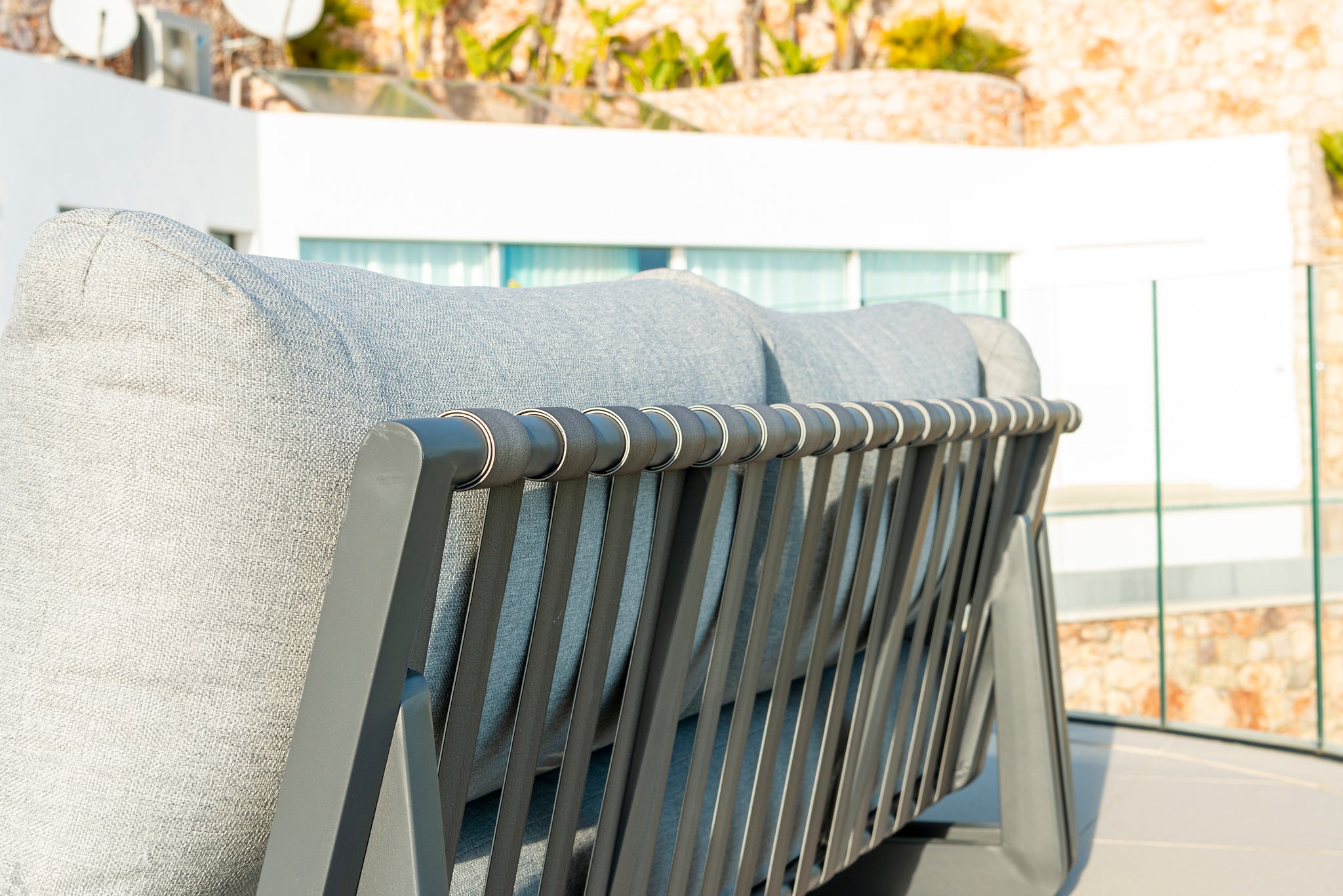 Grey outdoor modular sofa with metal frame on a patio close-up image of detail.