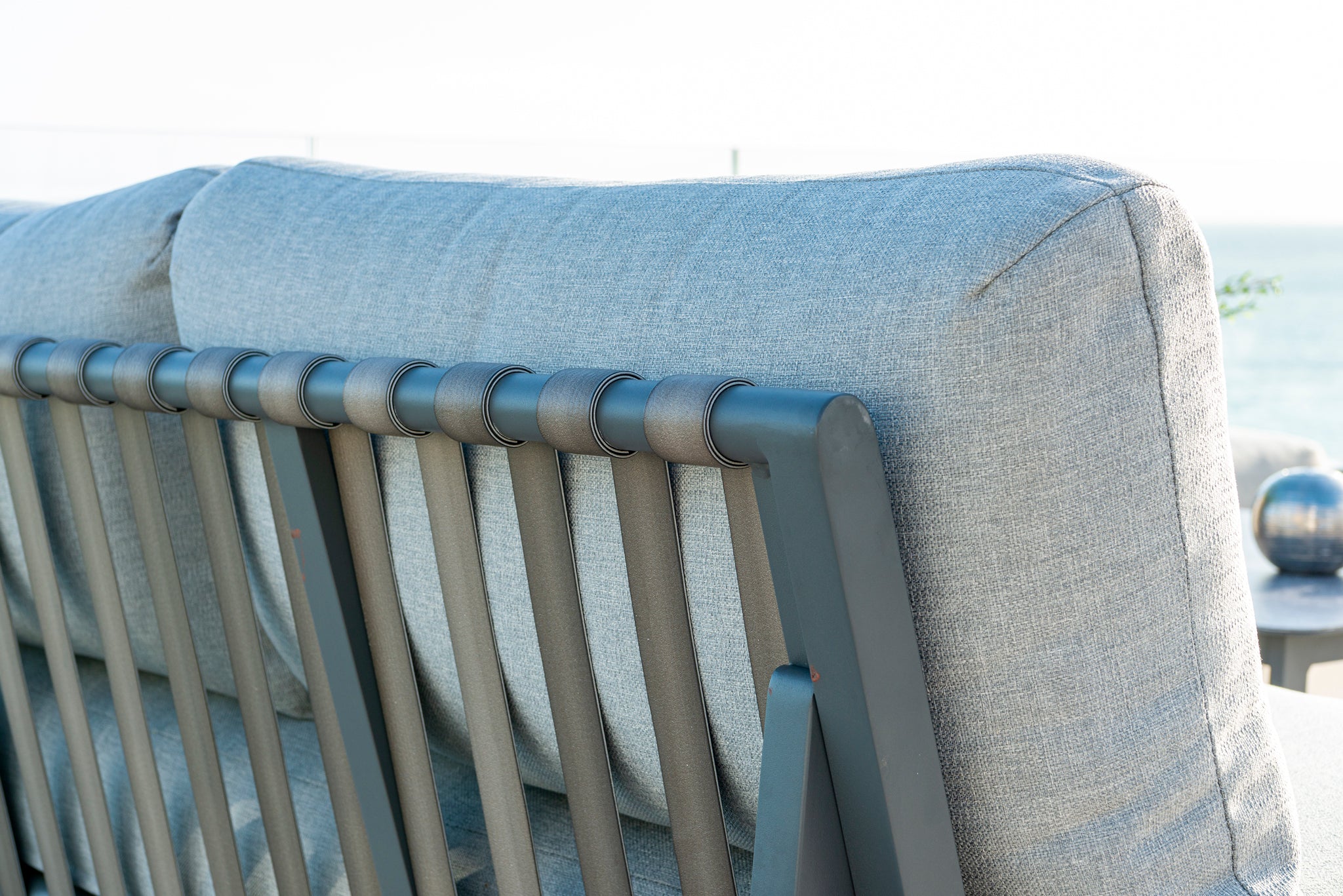 Close-up of Rimini modular outdoor sofa showing powder coated frame and deep light-grey cushions