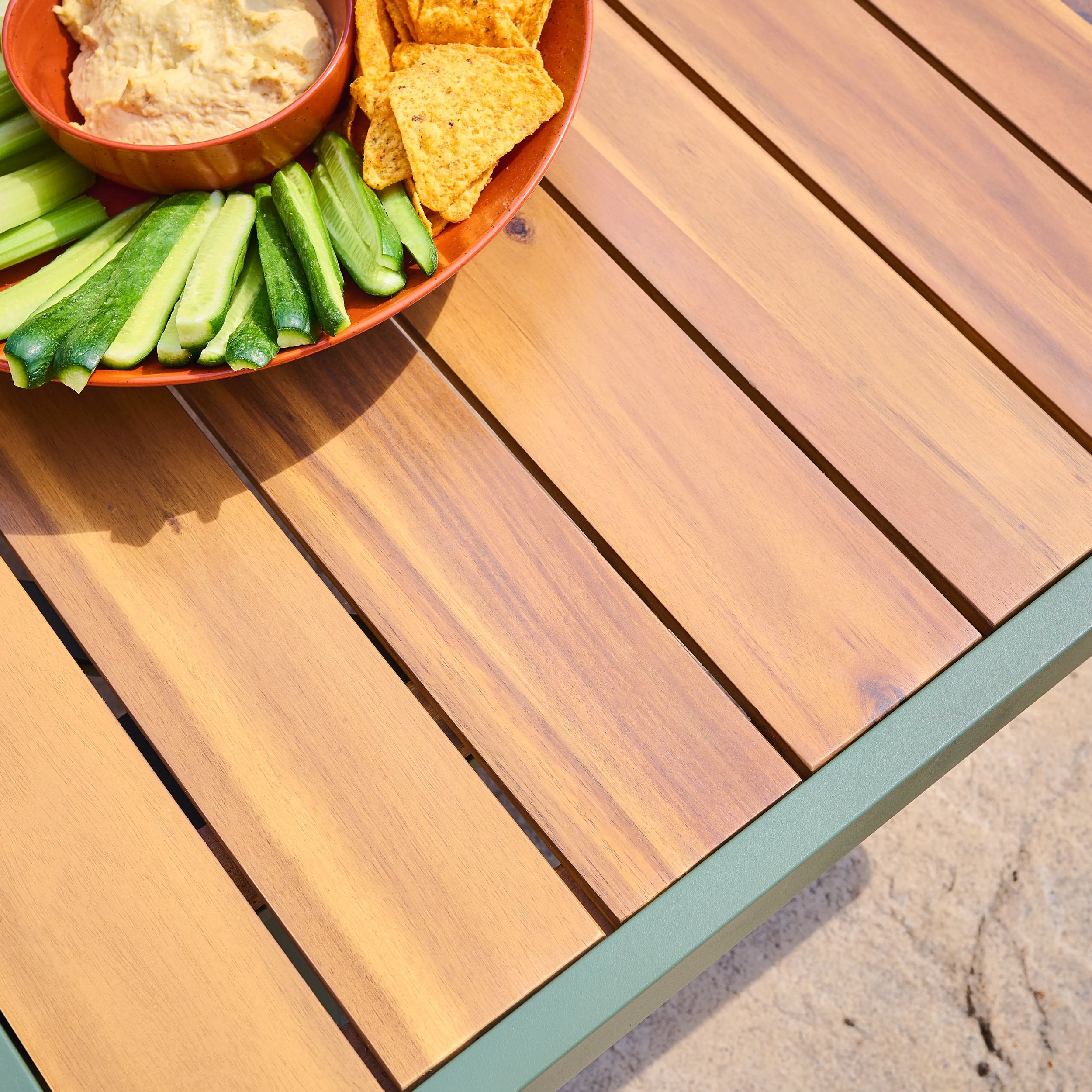 Bowl of hummus with chips and cucumbers on a wooden table top