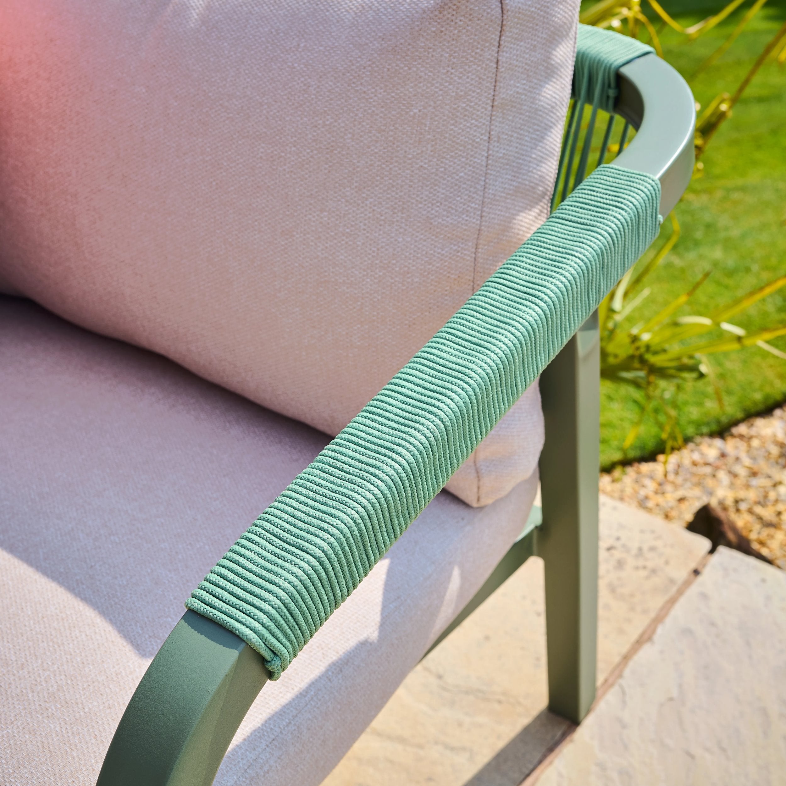 Close-up of a green chair armrest with a blurred outdoor background