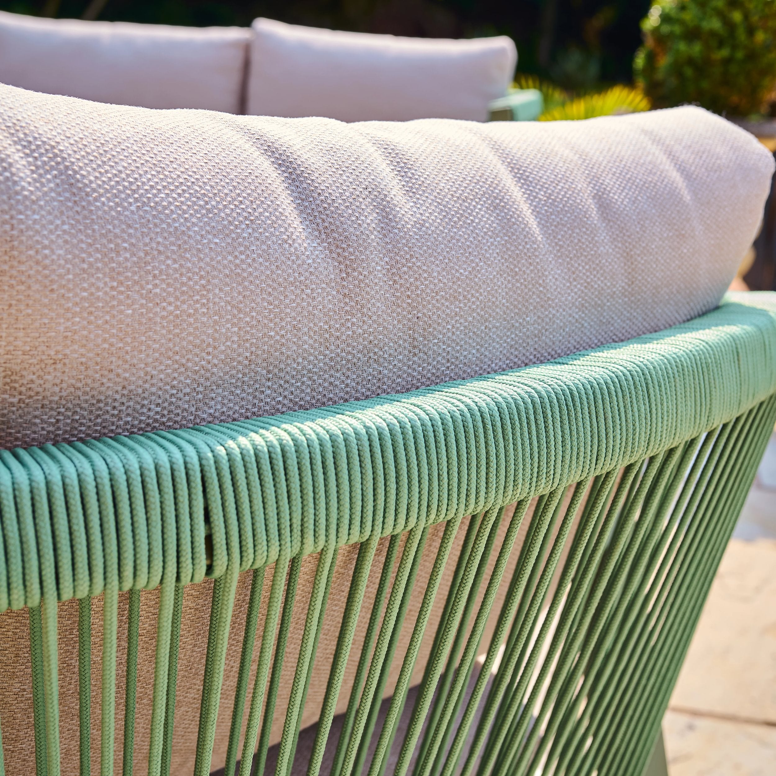 Green wicker chair with a light gray cushion in an outdoor setting