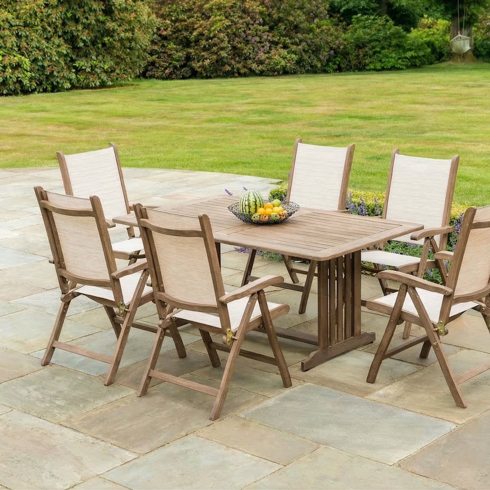6 folding outdoor chairs and a rectangular table on a patio near a lawn
