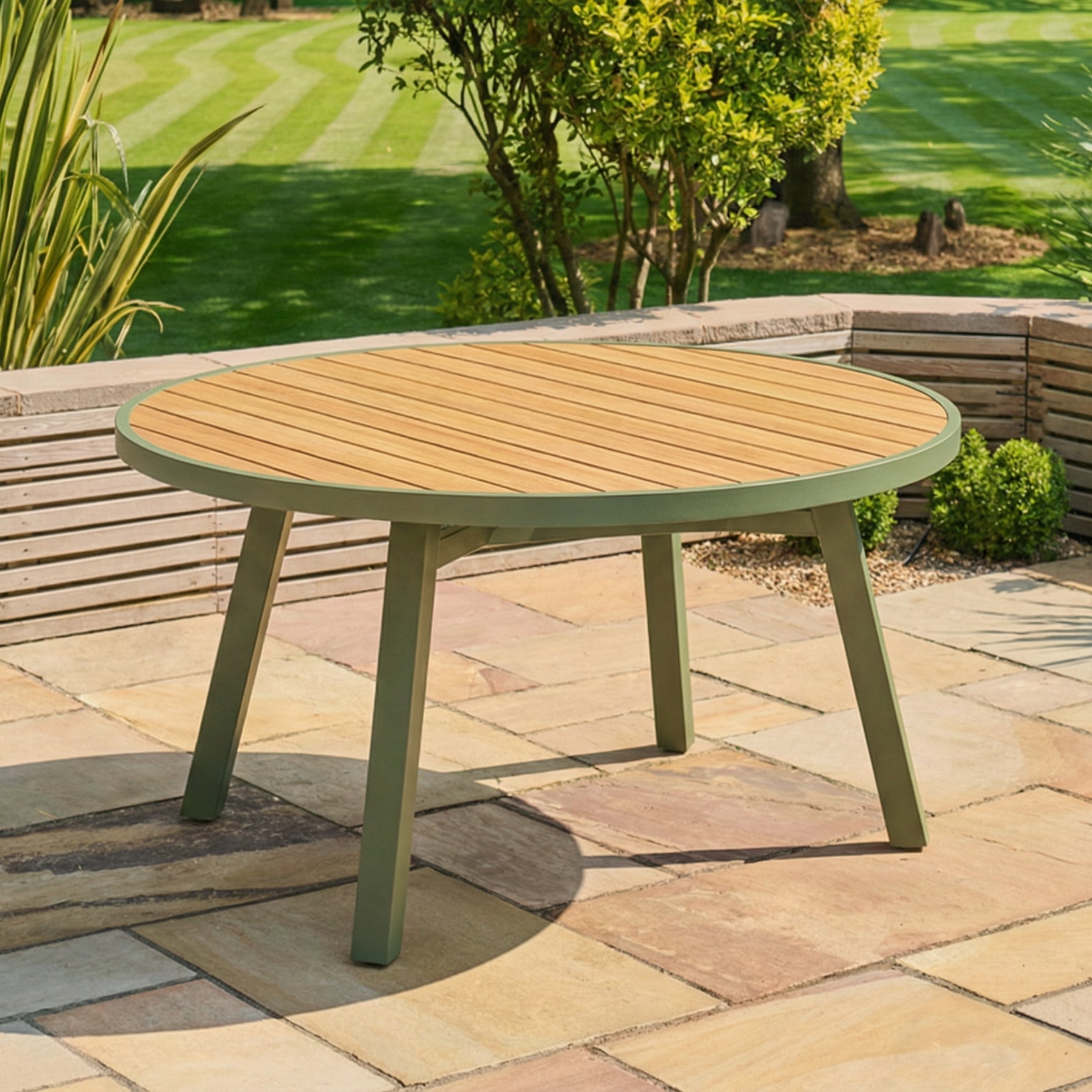 Round wooden table with green legs on a stone patio