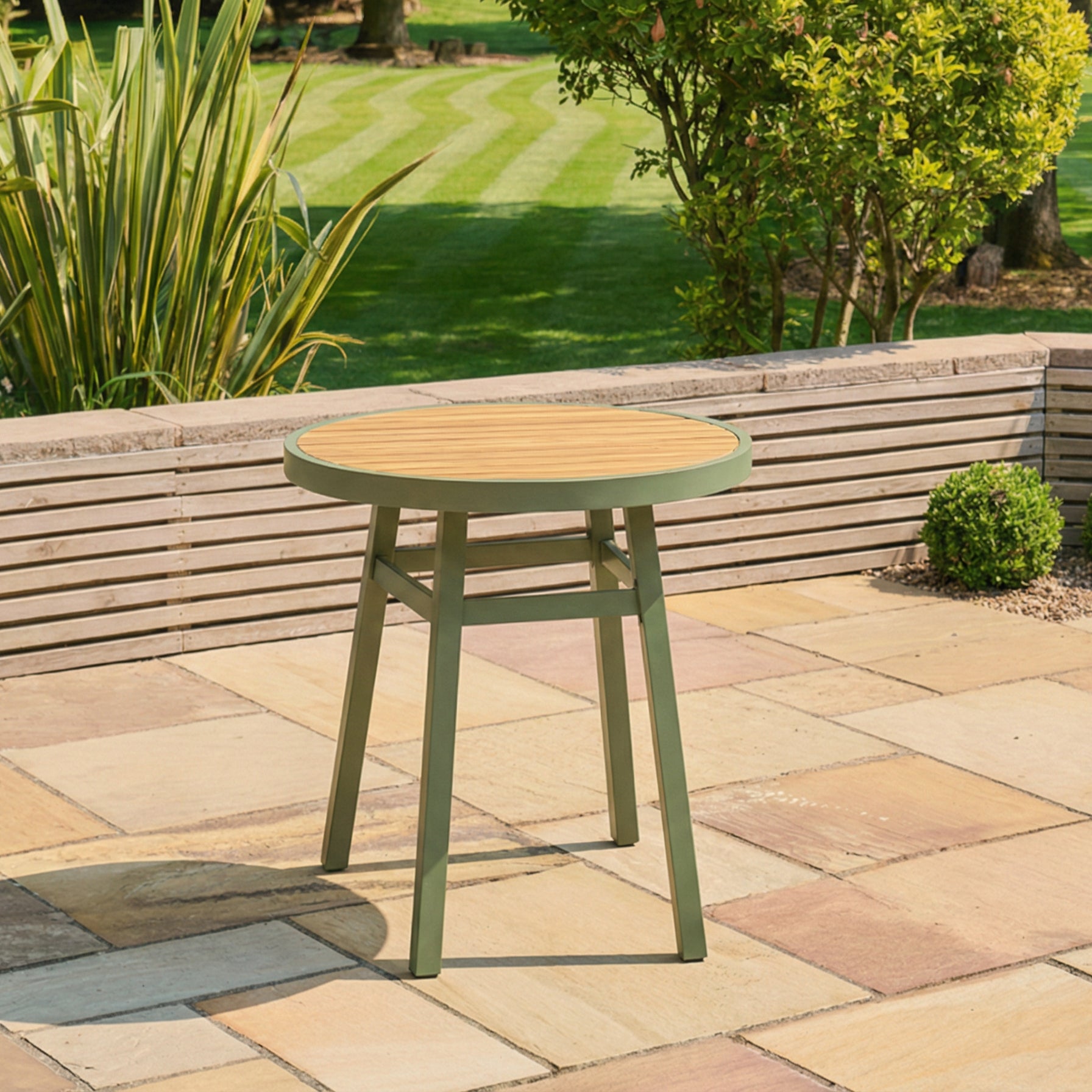 Green outdoor stool on a patio with grass and plants in the background