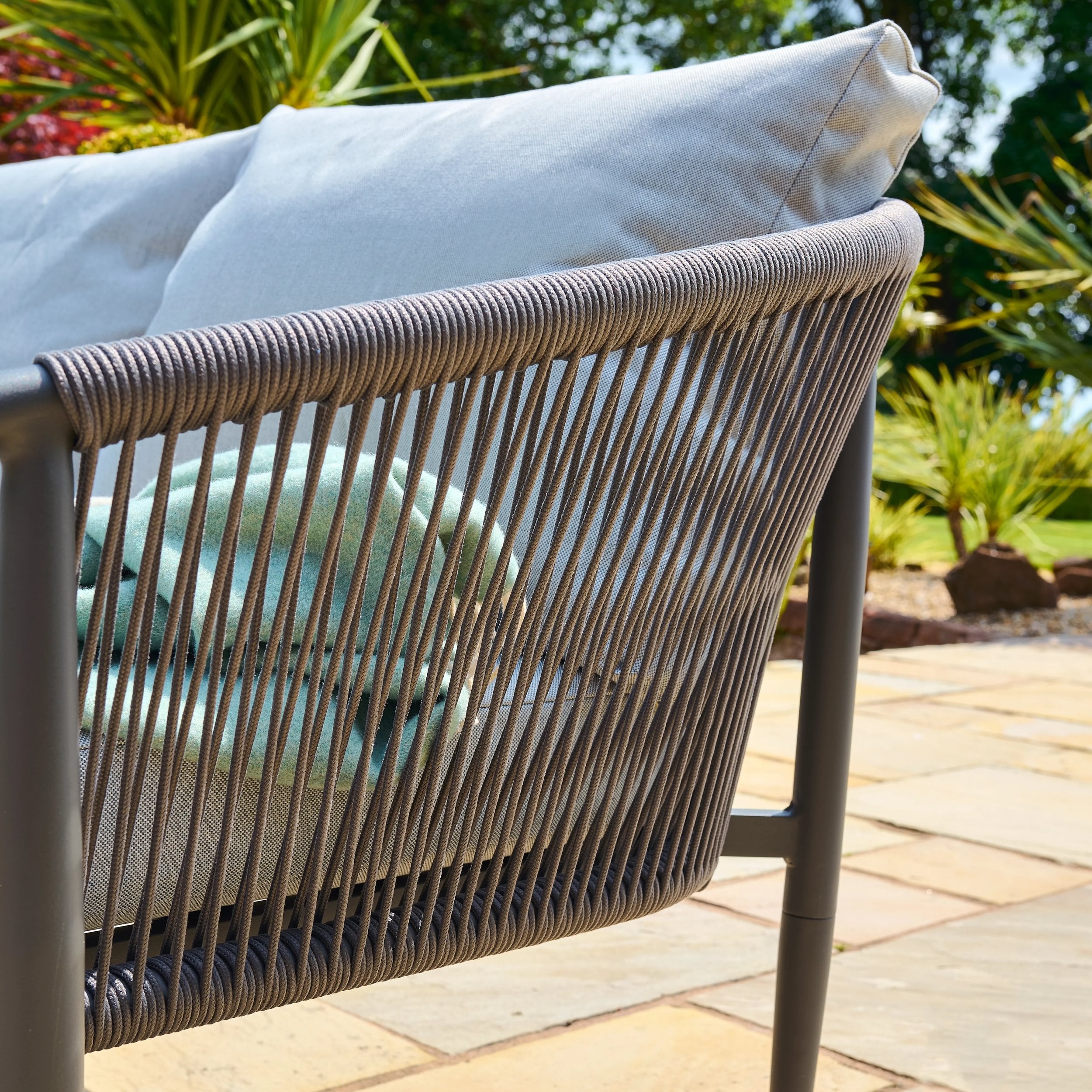 Outdoor chair with woven backrest and cushions on a patio