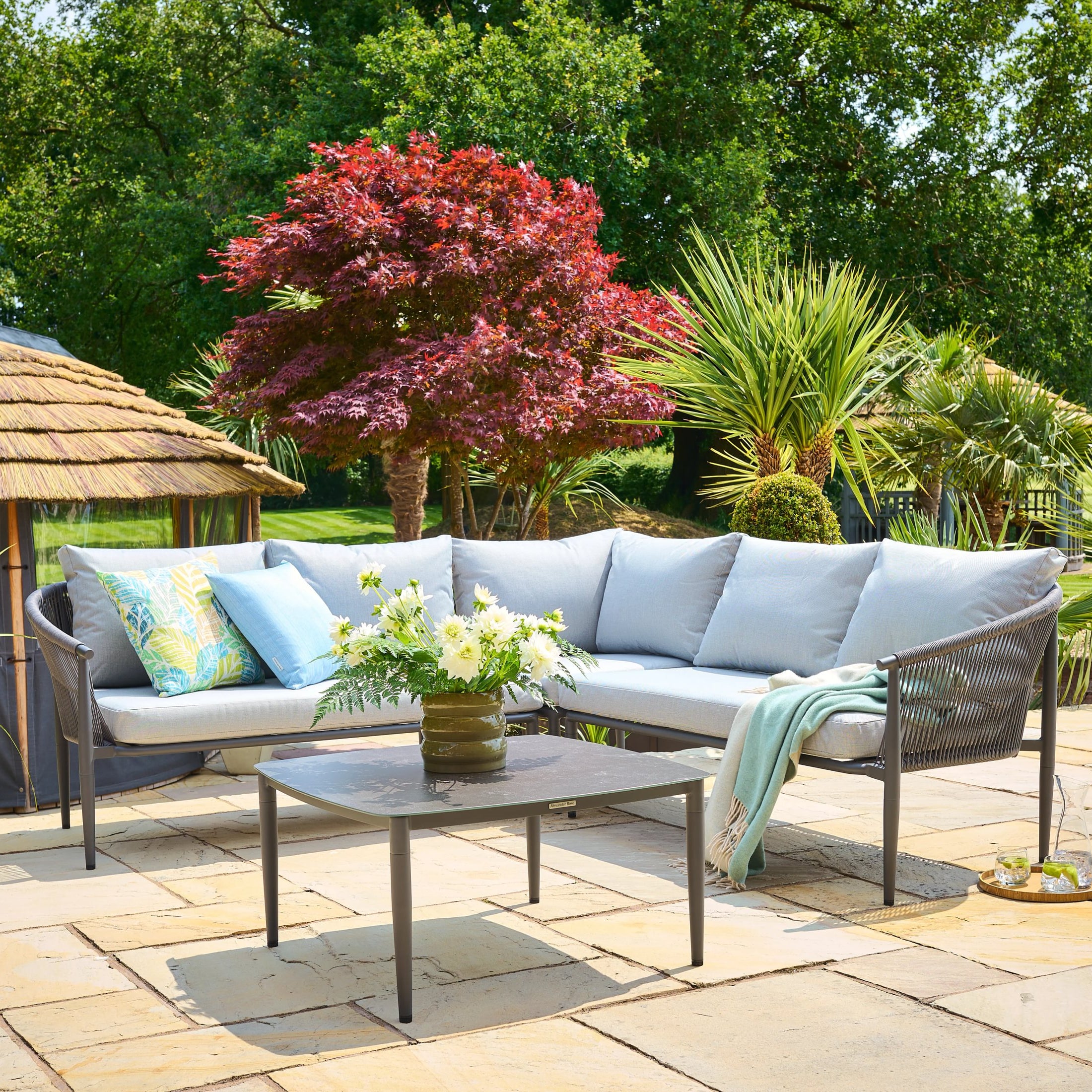 Outdoor patio with a sectional sofa, coffee table, and decorative elements on a stone patio.