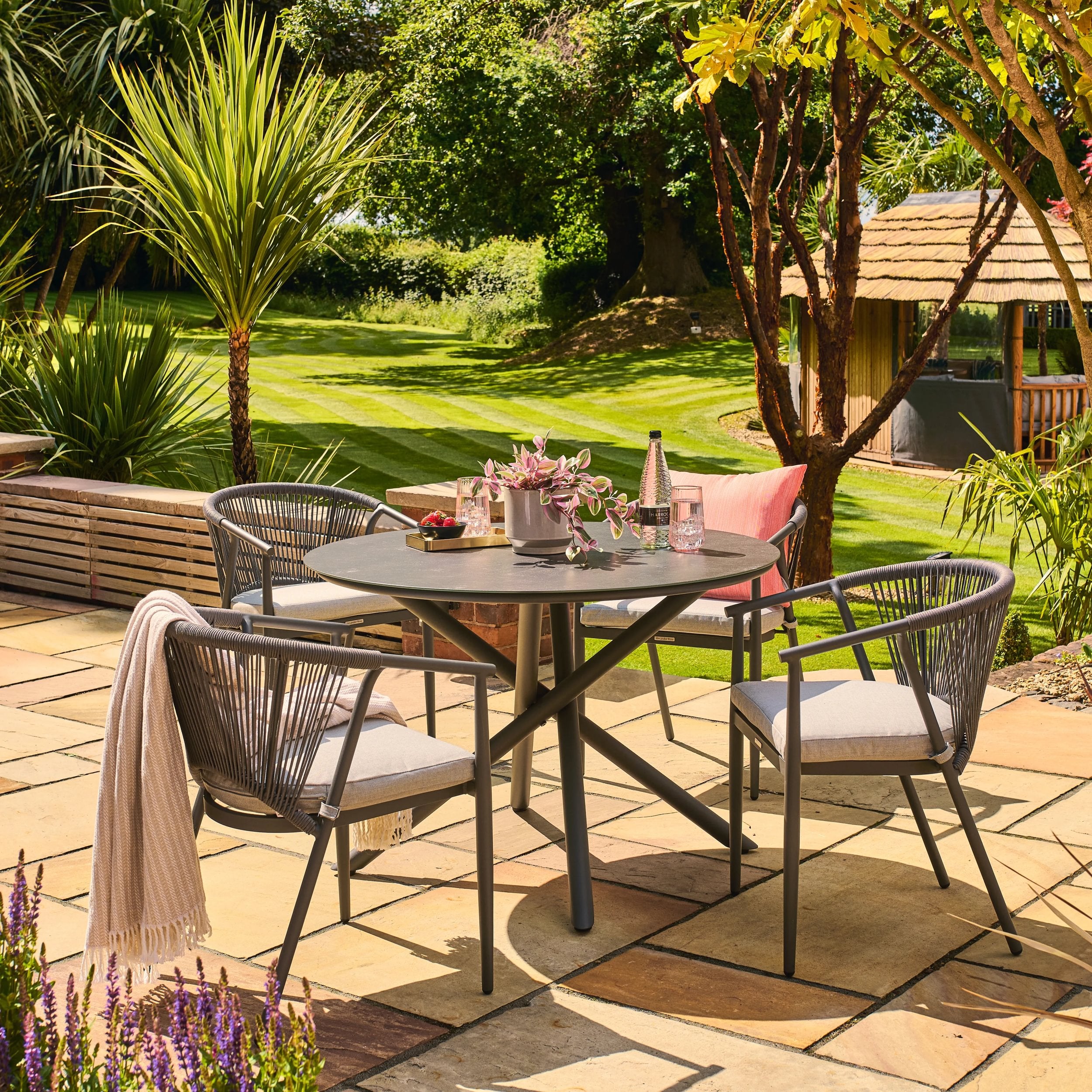 Kyoto outdoor patio setting with a round table and chairs on a paved area, surrounded by greenery.