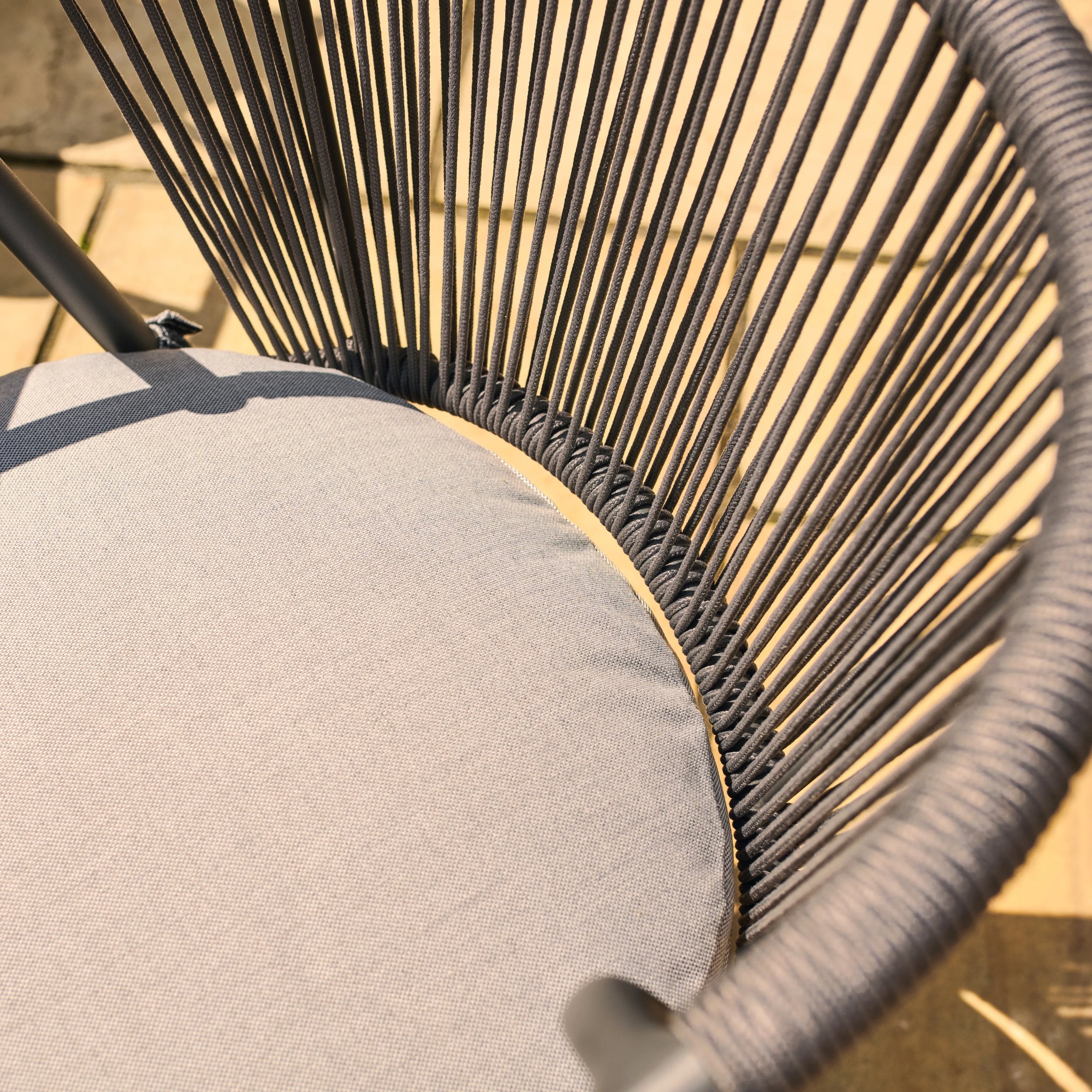 Kyoto close-up of a chair with woven backrest and gray cushion on a wooden floor.