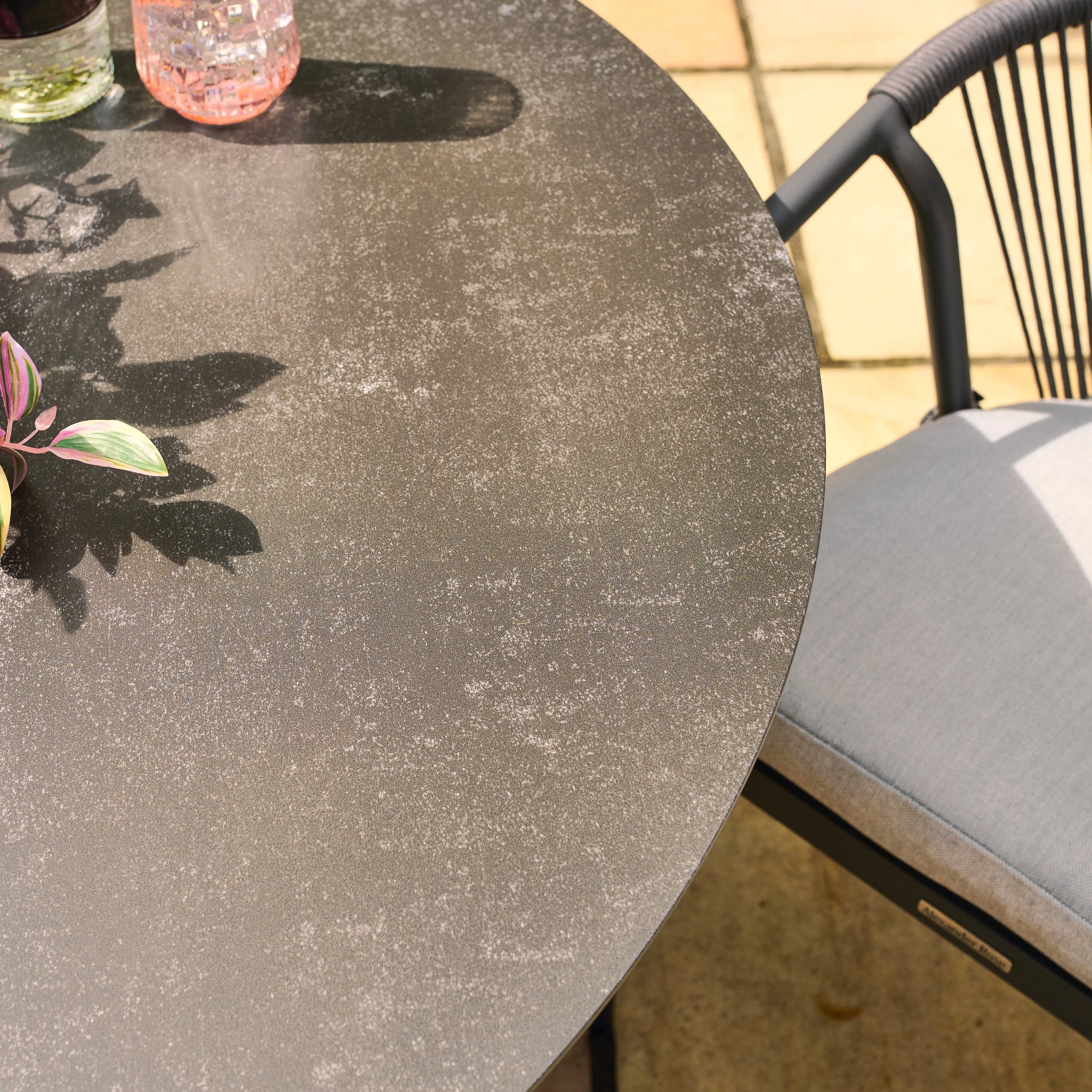 Kyoto round concrete table with a chair and plant on a patio