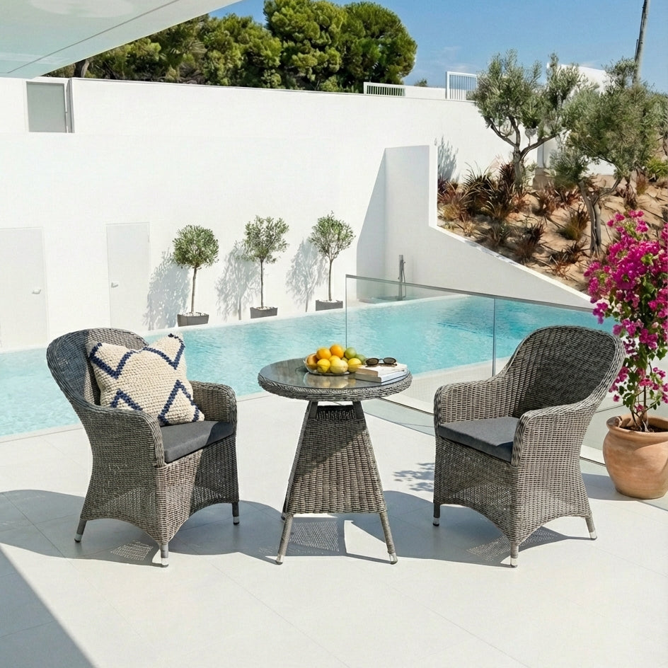 Outdoor patio set with two chairs and a small table by a poolside.