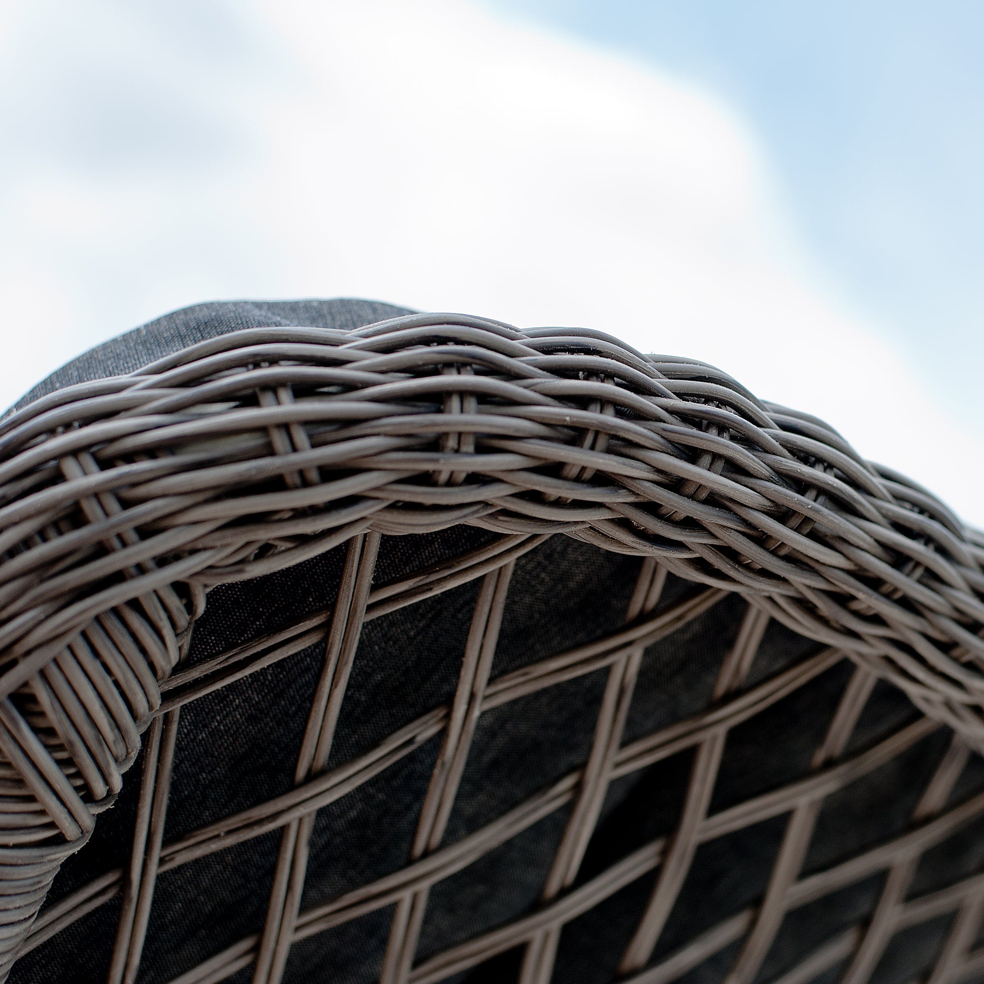 Close-up of a woven chair with a blurred blue sky background