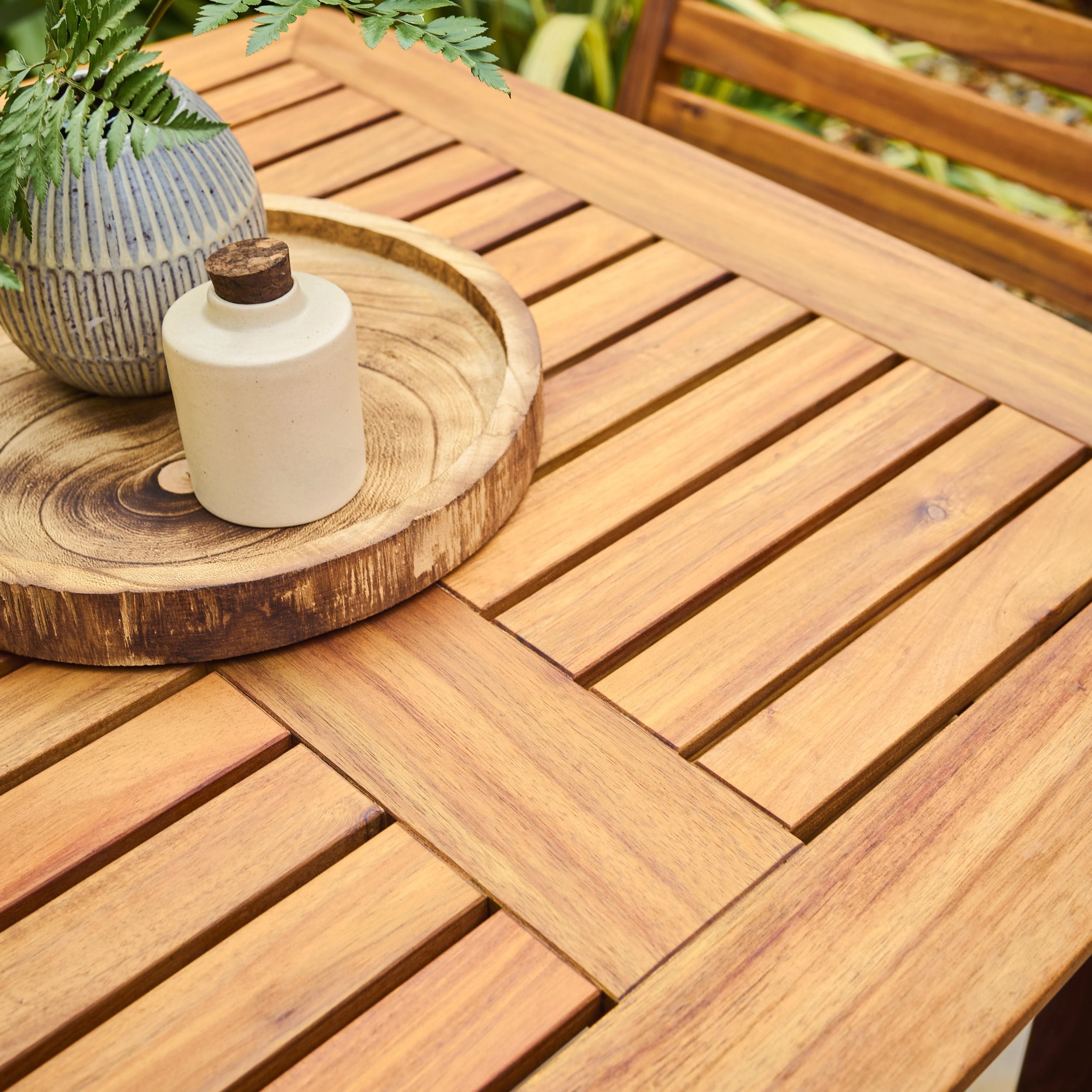 Wooden table with a wooden tray and white container on a blurred natural background