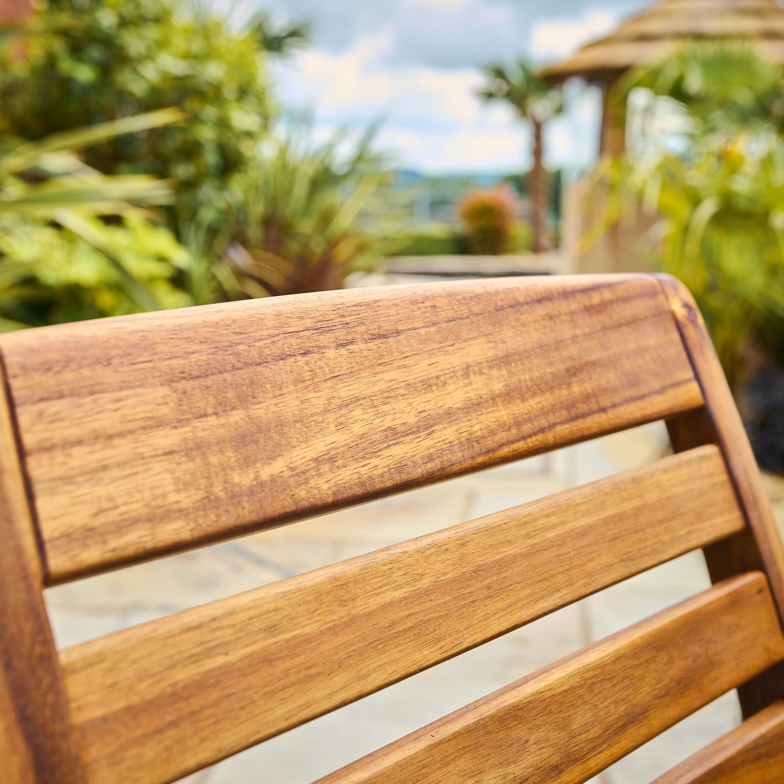 Close-up of a wooden chair with a blurred garden background